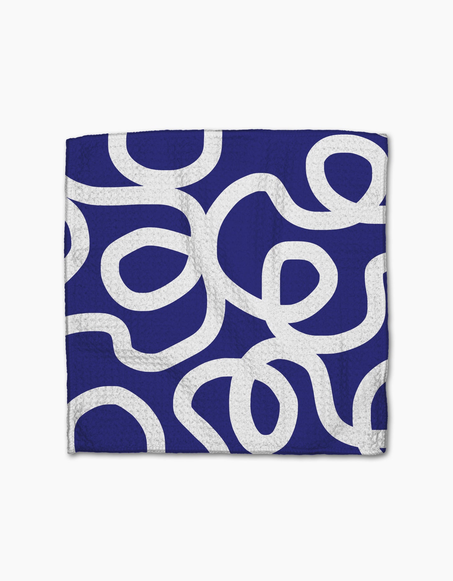 The Wander napkin by Rachel Parker features a folded dark blue design with thick, white curvy abstract lines and is crafted from recycled materials for a modern, playful touch.