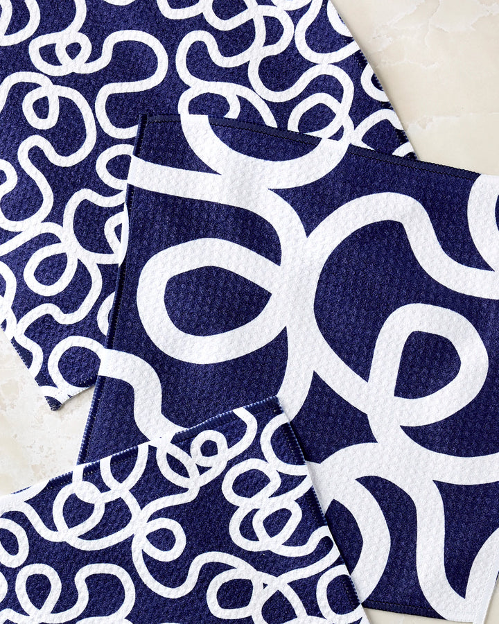 Three "Wander" dishcloths by Rachel Parker in navy blue, each featuring bold white squiggly lines, are shown overlapping on a light surface.