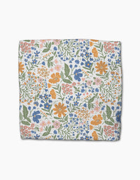 The Wildflower Vine Blush dishcloth by Danelys Sidron features a densely packed floral pattern in orange, blue, pink, and green on white Geoweave fabric, and is crafted from recycled materials.