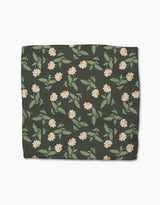 The Danelys Sidron Wildflower Vine Onyx is a dark green rectangular blanket made from recycled materials, featuring a repeating white and yellow floral pattern with green leaves, shown on a white background.