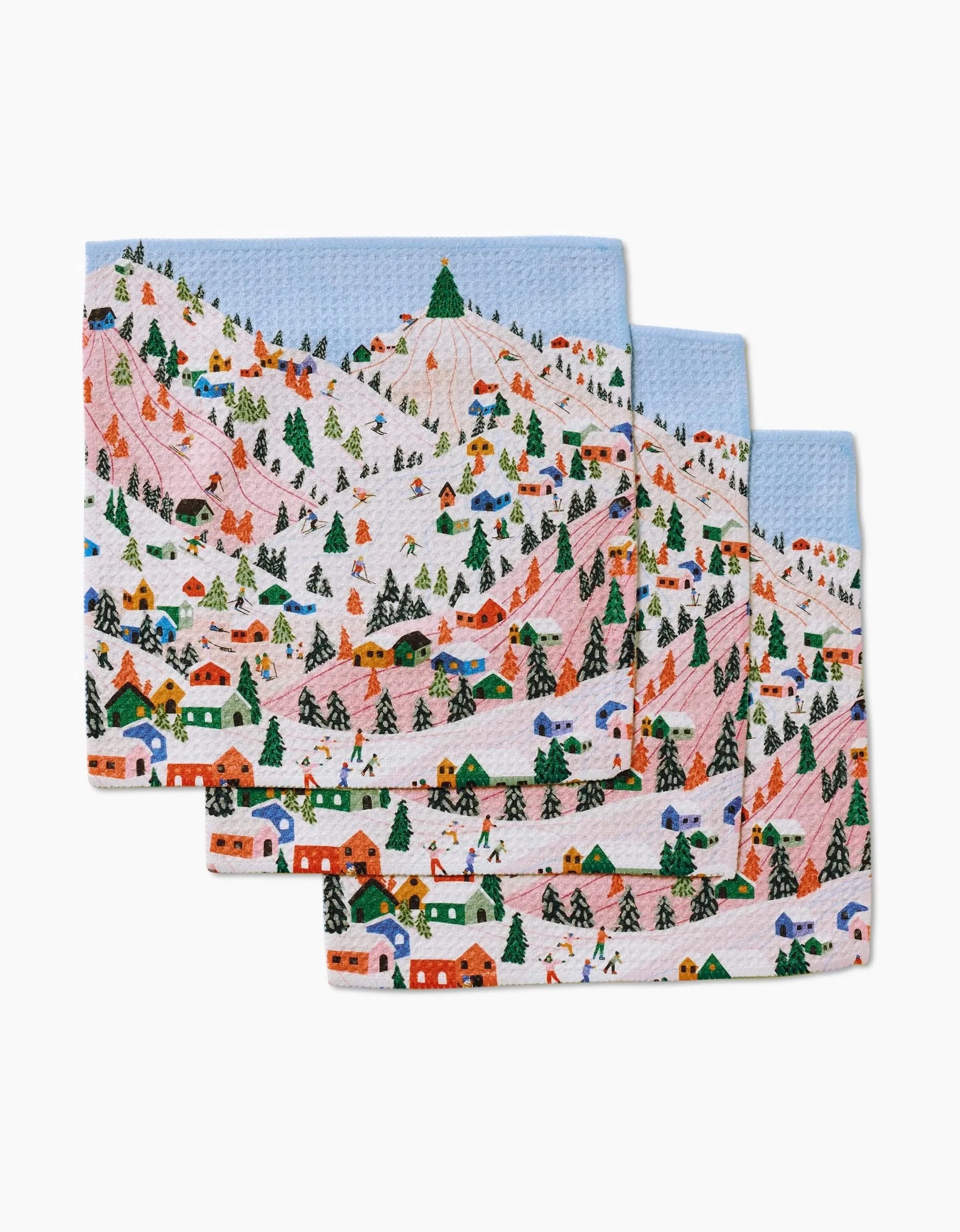 The Ceyda Alasar Winter Holiday set includes three Geoweave dishcloths with a vibrant winter village and mountain scene, complete with snow, trees, houses, skiers, and a blue sky.