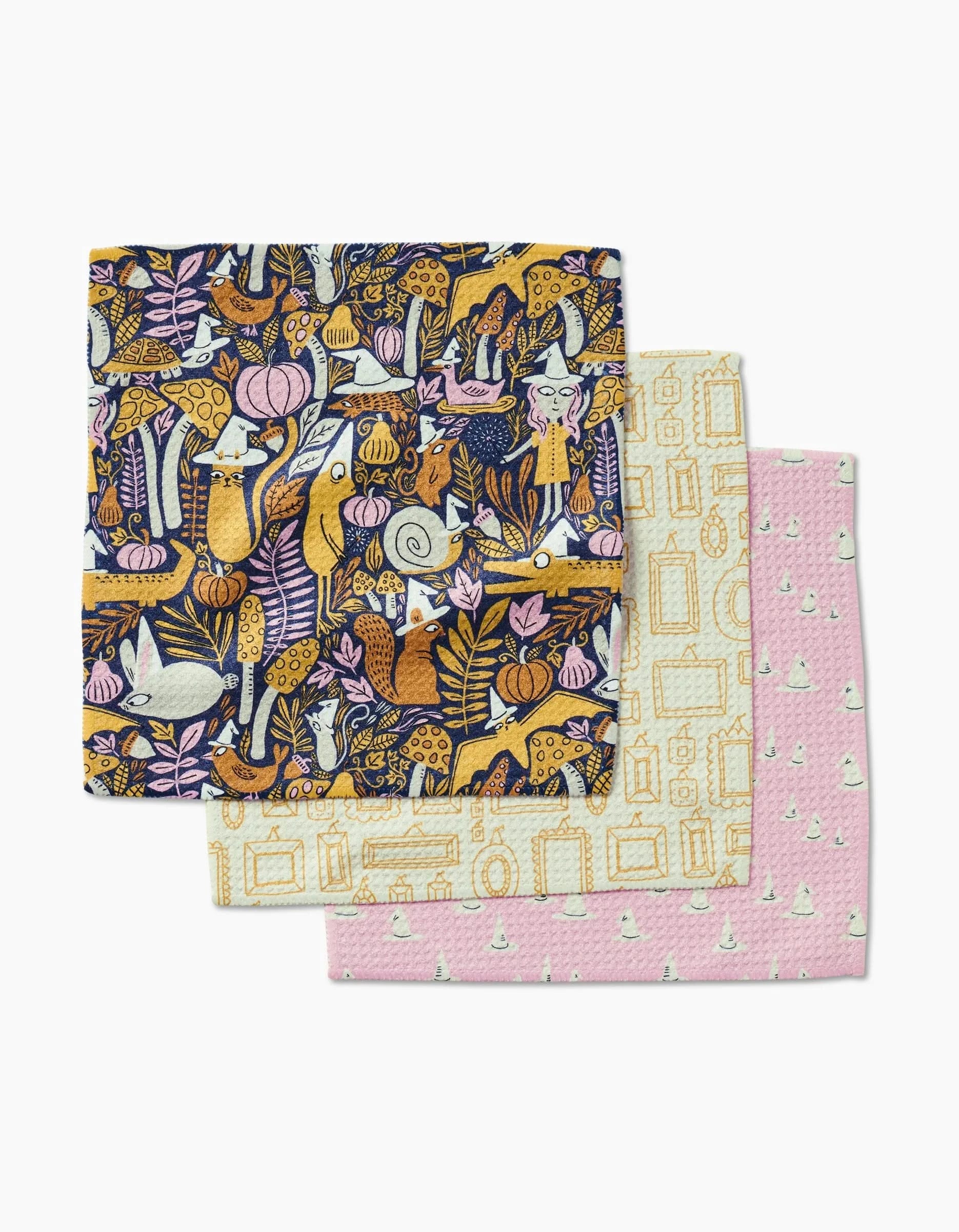 Three decorative dishcloths from Amy MacCready’s Witchy Season are stacked: the top shows whimsical animals and plants, the middle has a beige geometric frame on white, and the bottom is pink with white sailboats. Made from recycled materials.