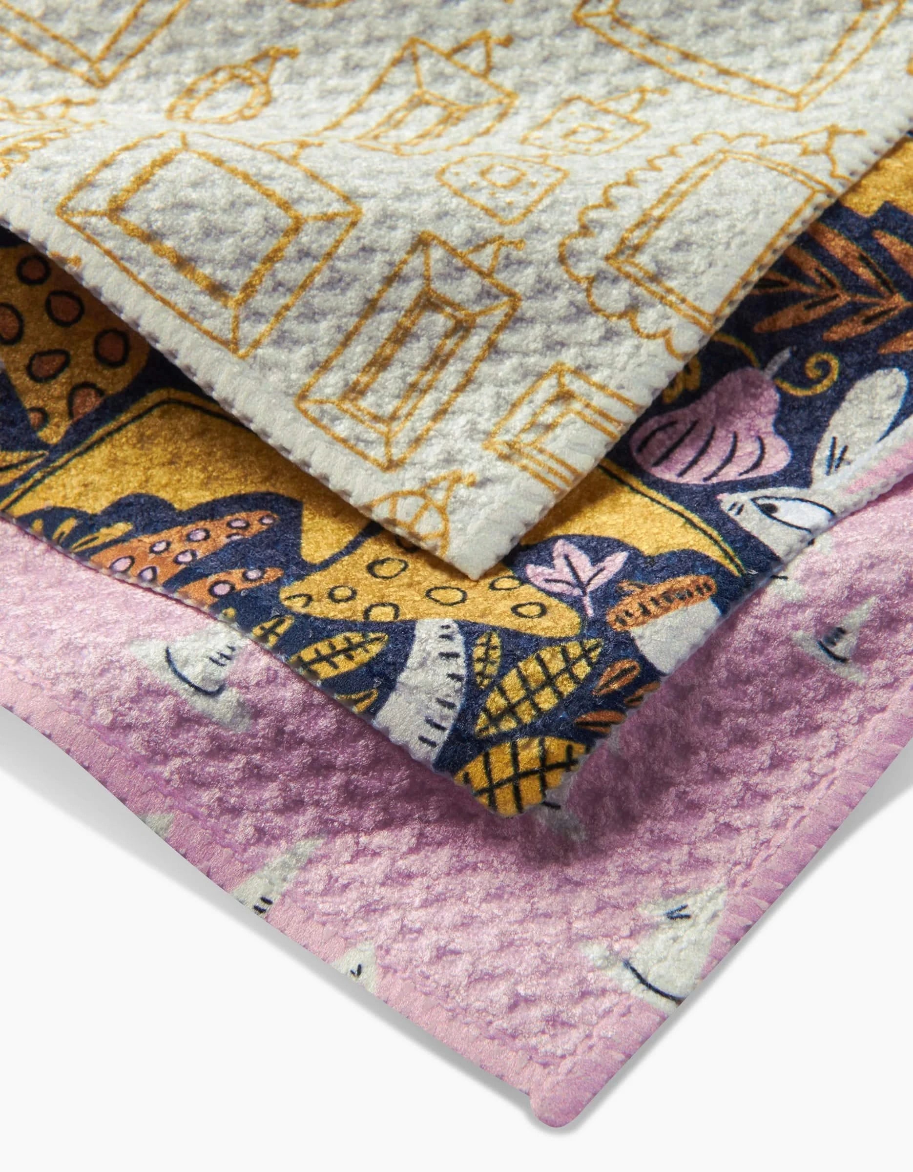 The Witchy Season dishcloth set by Amy MacCready features three Geoweave cloths with unique patterns: yellow and gray frames, blue and yellow abstracts, and pink and white leaves—durable, colorful, and stacked for style.