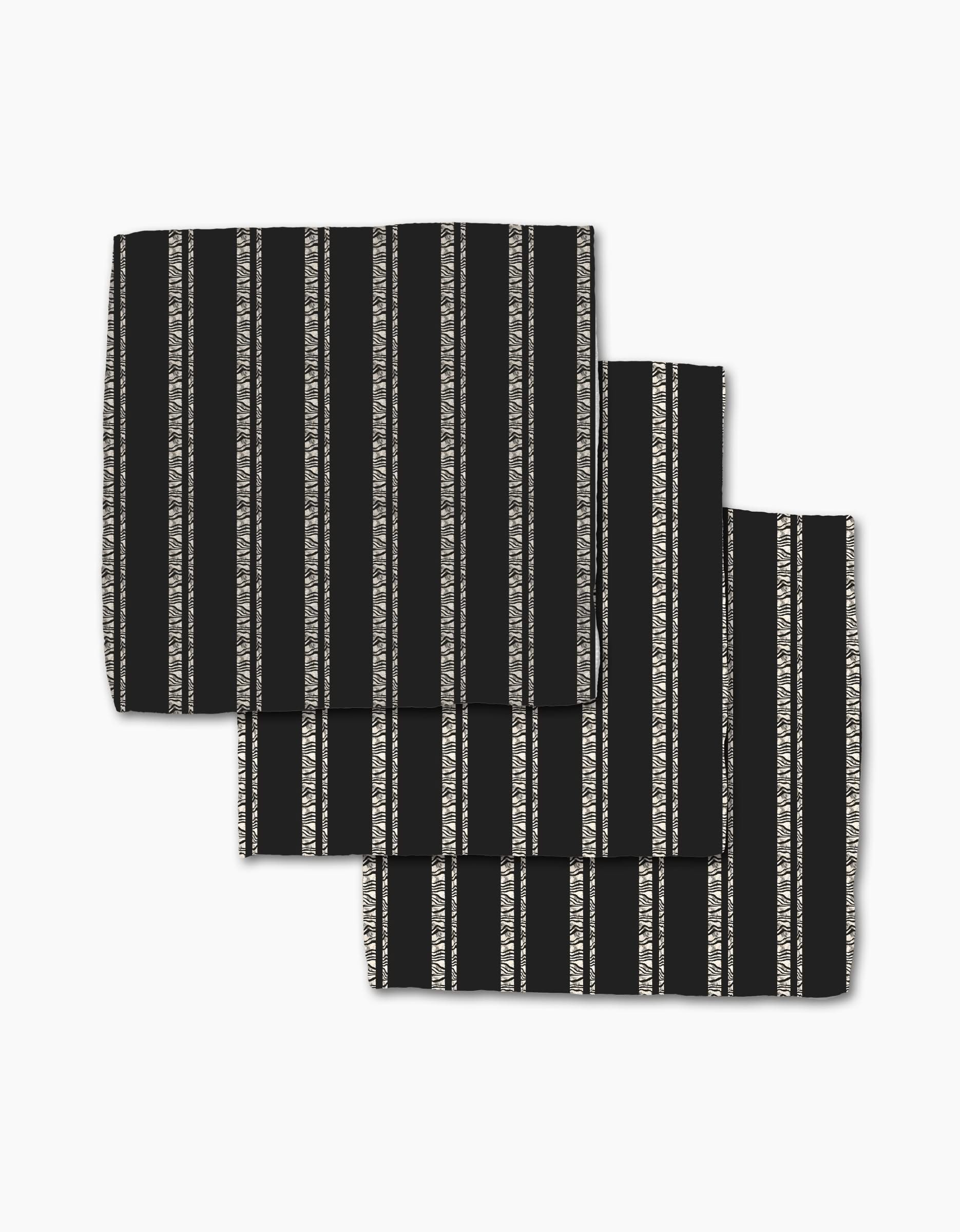 Three Zebra Pin Stripe Black cloth napkins from Geometry, made with Geoweave fabric and featuring vertical white and gray stripes, are neatly folded in a slightly overlapping arrangement on a white background.