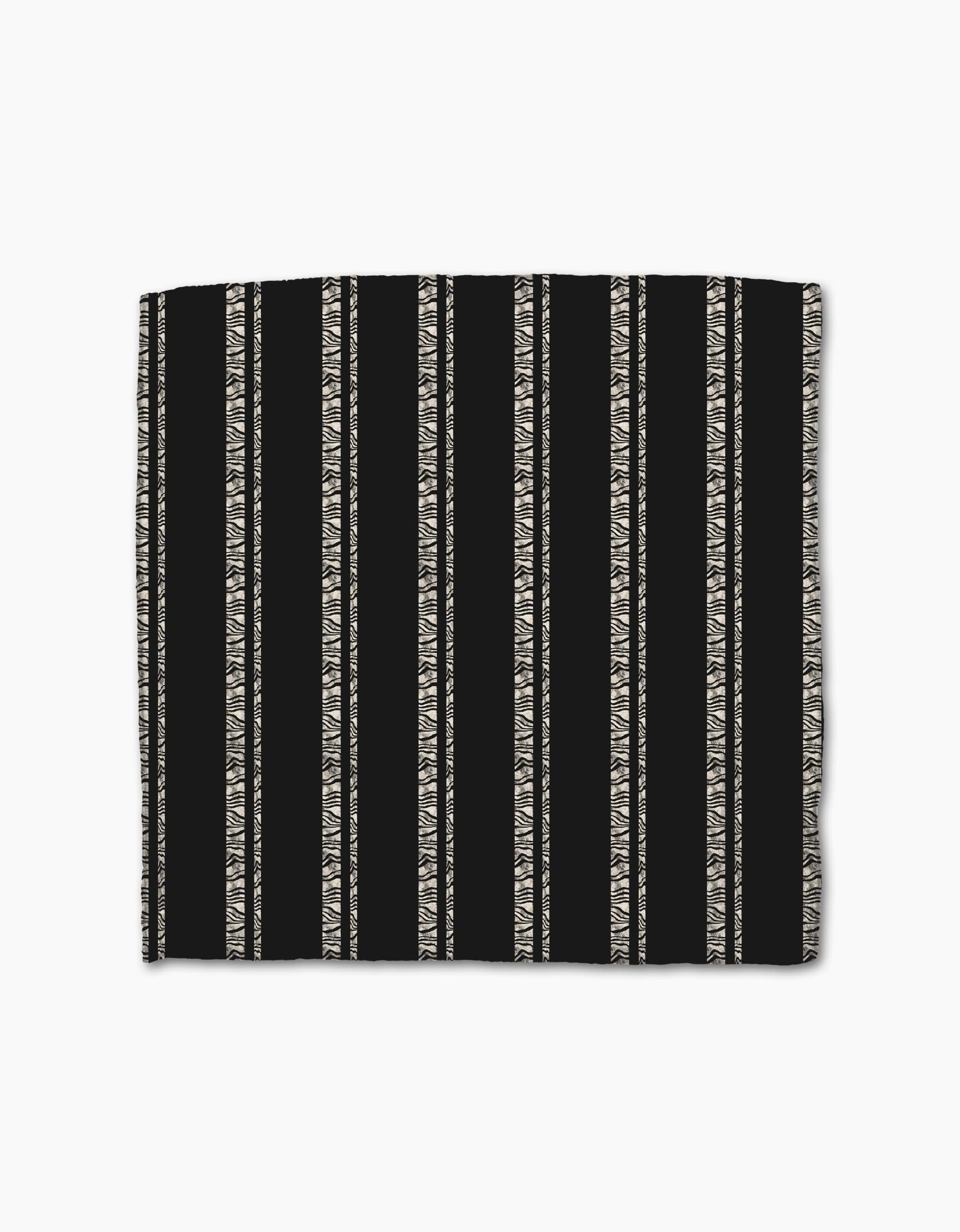 The Zebra Pin Stripe Black by Geometry is a black rectangular dishcloth made from recycled Geoweave fabric, featuring beige zigzag and triangle stripes with solid black sections between patterns.