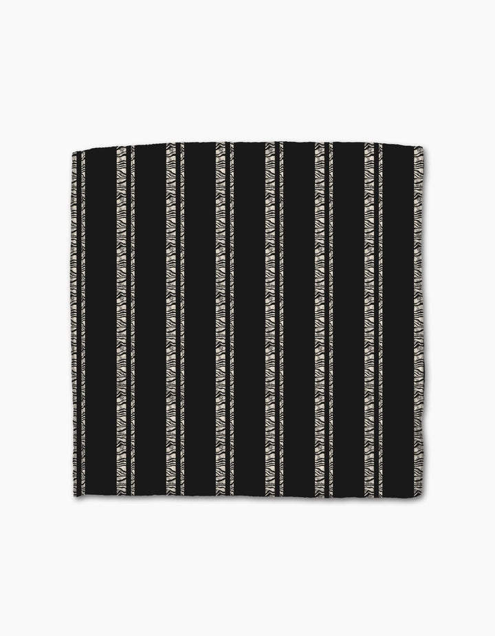 The Zebra Pin Stripe Black by Geometry is a black rectangular dishcloth made from recycled Geoweave fabric, featuring beige zigzag and triangle stripes with solid black sections between patterns.