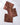 Three Rustle square cloth napkins by Geometry, featuring a brown and tan leaf pattern and made from recycled materials, are arranged overlapping on a white marble surface.