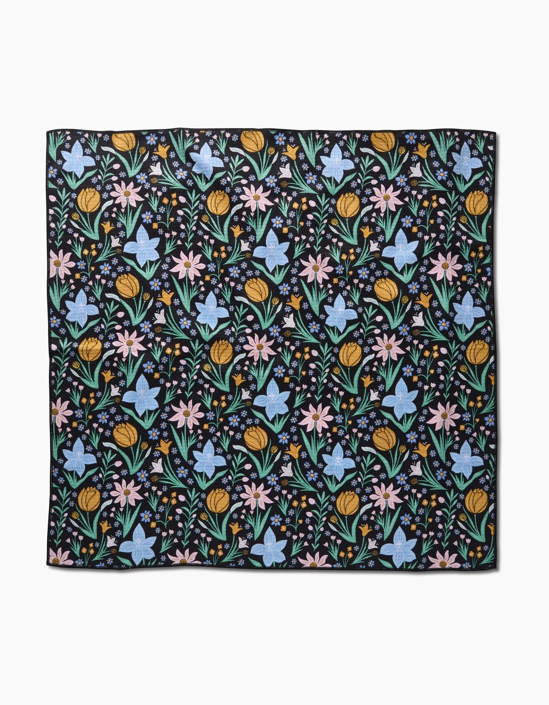 The Garden of Light by Danelys Sidron is a square fabric with a black background and a repeating pattern of colorful yellow, pink, and blue flowers with green leaves, made from highly absorbent post-consumer recycled materials.