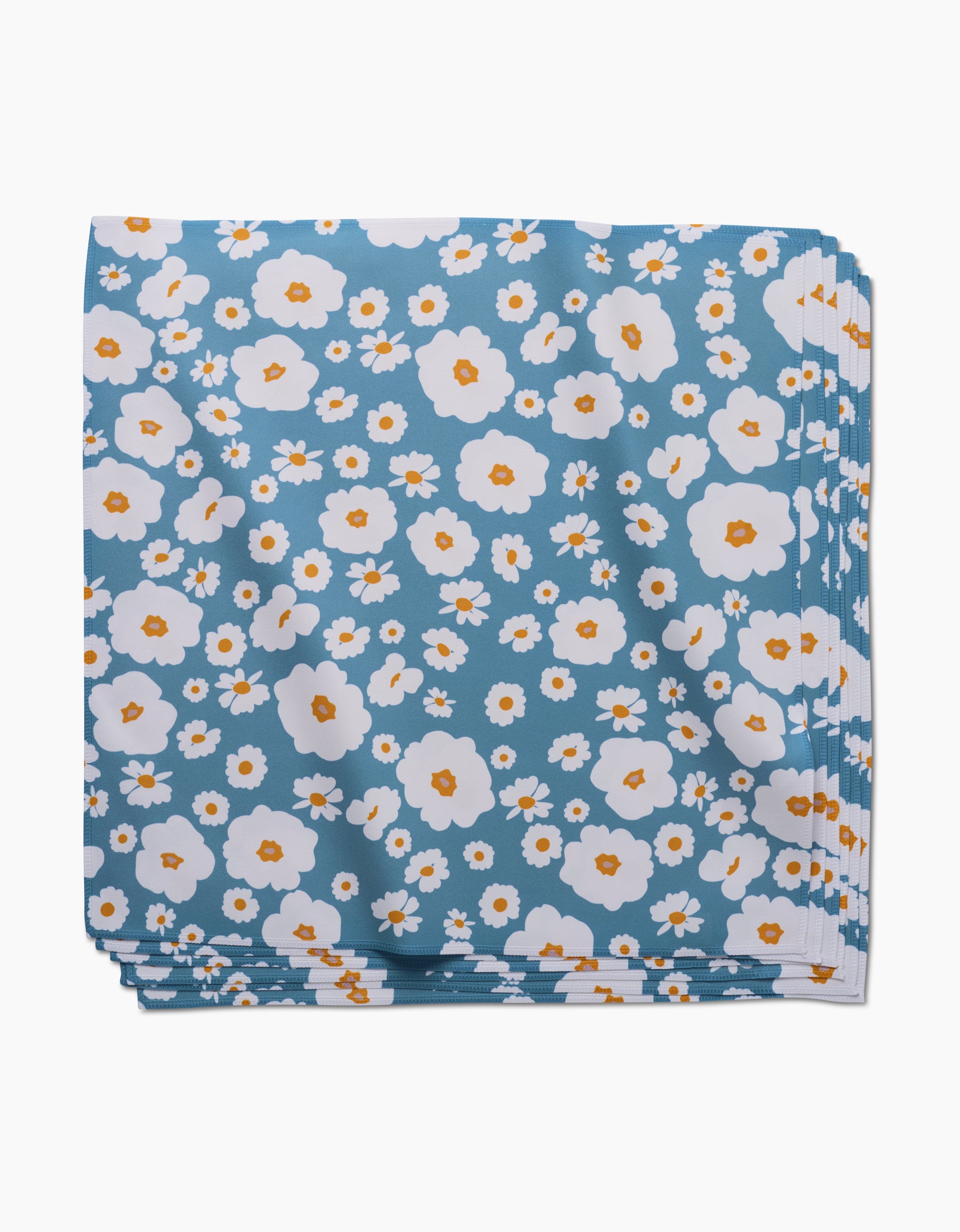 The GEOMETRY Happy Daysies Dinner Napkin Set is folded, made from Geosuede fabric, and features a blue background with white and orange flower patterns.