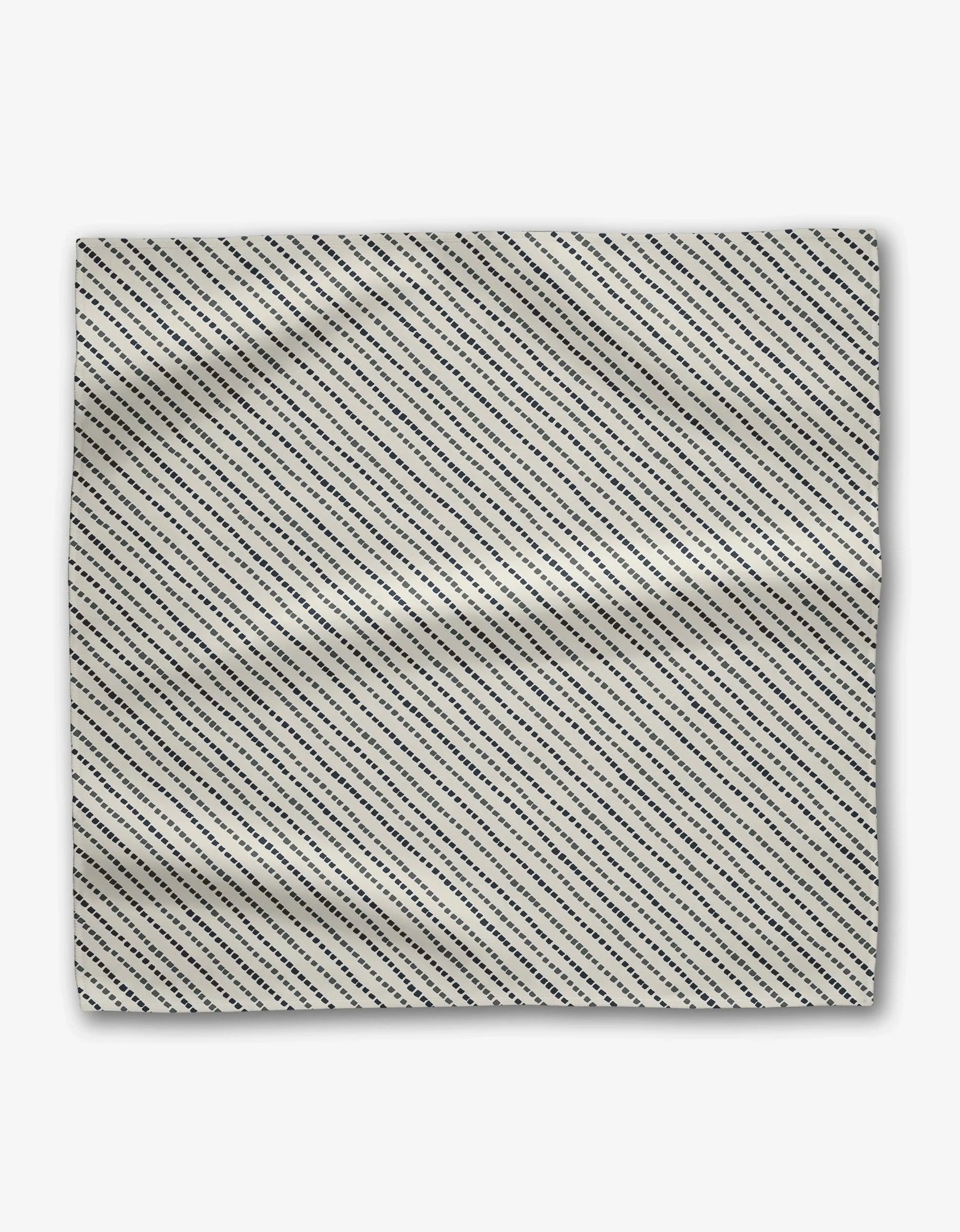 The Kealia Dinner Napkin Set by GEOMETRY features white Geosuede fabric with evenly spaced diagonal black dashed lines from top left to bottom right and a slightly wrinkled look.