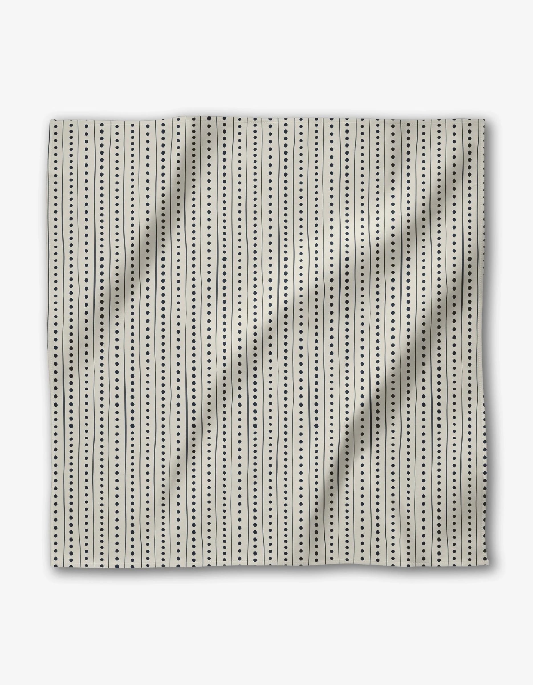 Kealia by GEOMETRY features beige Geosuede fabric with evenly spaced vertical black dotted lines for a minimalist, modern look. Made from recycled materials, the slightly wrinkled fabric adds subtle texture.