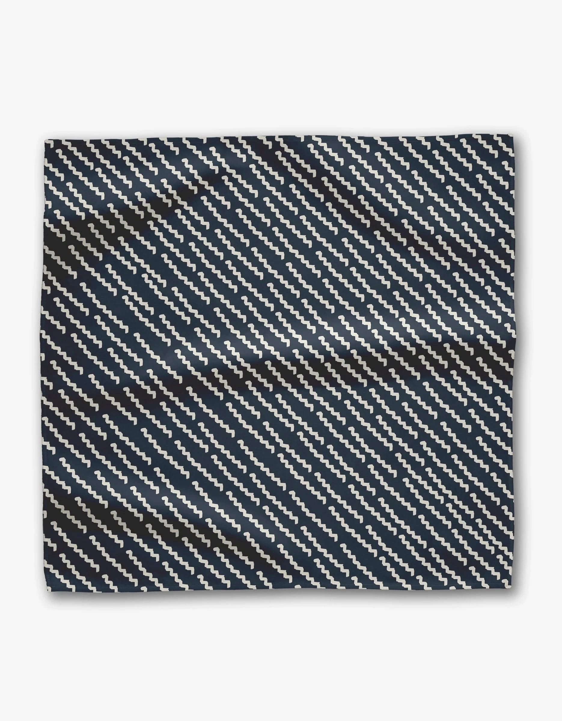 The Kealia dinner napkin set by GEOMETRY features Geosuede fabric with a dark blue background and white zigzag lines in a diagonal pattern, shown flat with subtle creases.