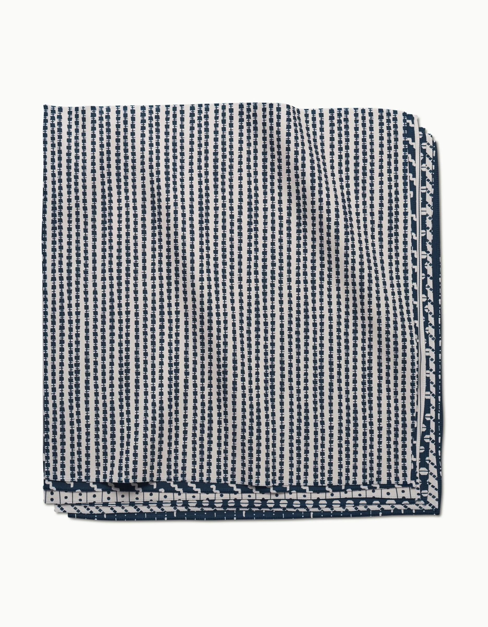 The GEOMETRY Kealia Dinner Napkin Set, made from soft Geosuede fabric, features a navy blue and white geometric dot and stripe design neatly folded on a white background.