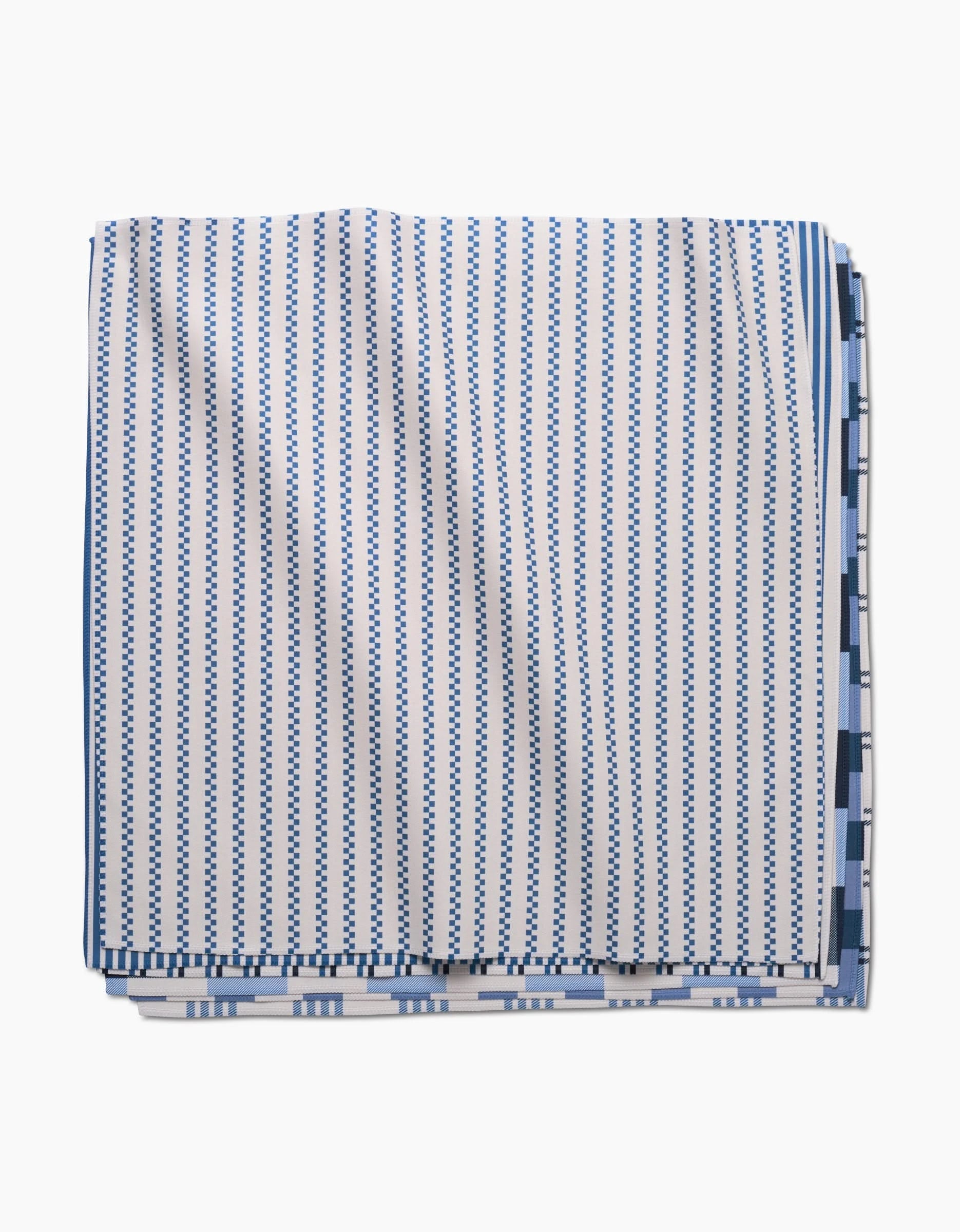 The GEOMETRY Seafaring Dinner Napkin, made from Geosuede fabric, showcases vertical blue and white stripes with small blue geometric designs, and is displayed against a white background.