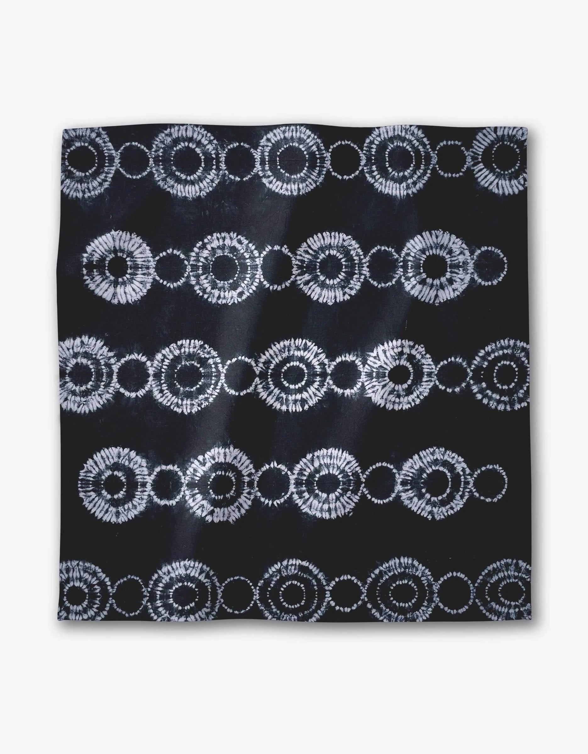 Shibo by GEOMETRY is a square dark Geosuede fabric with white circular patterns in horizontal rows on black, evoking a tie-dye or batik style.
