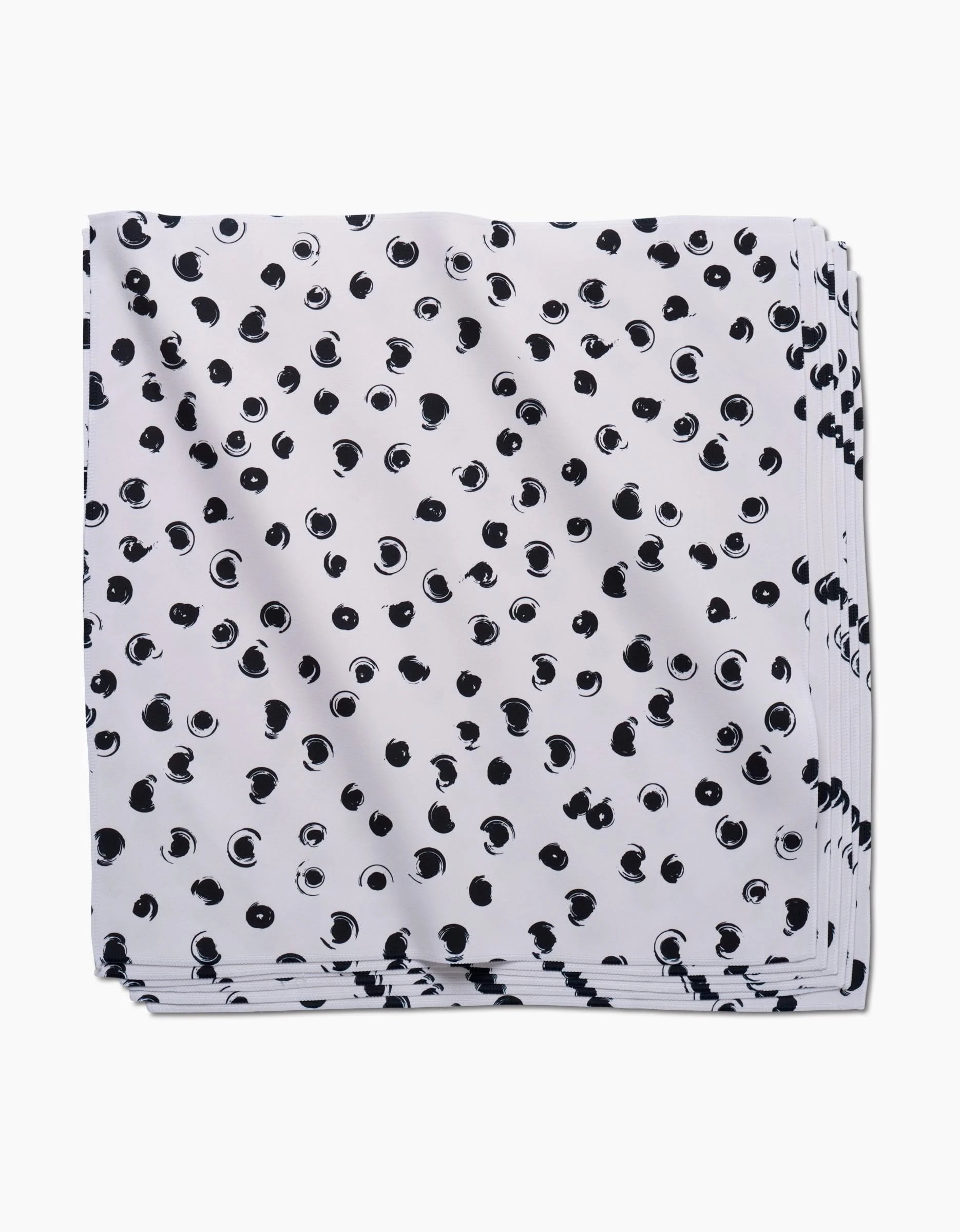 The GEOMETRY Tiny Drops napkin, made from white Geosuede fabric with a scattered black polka dot pattern, is shown folded against a white background.