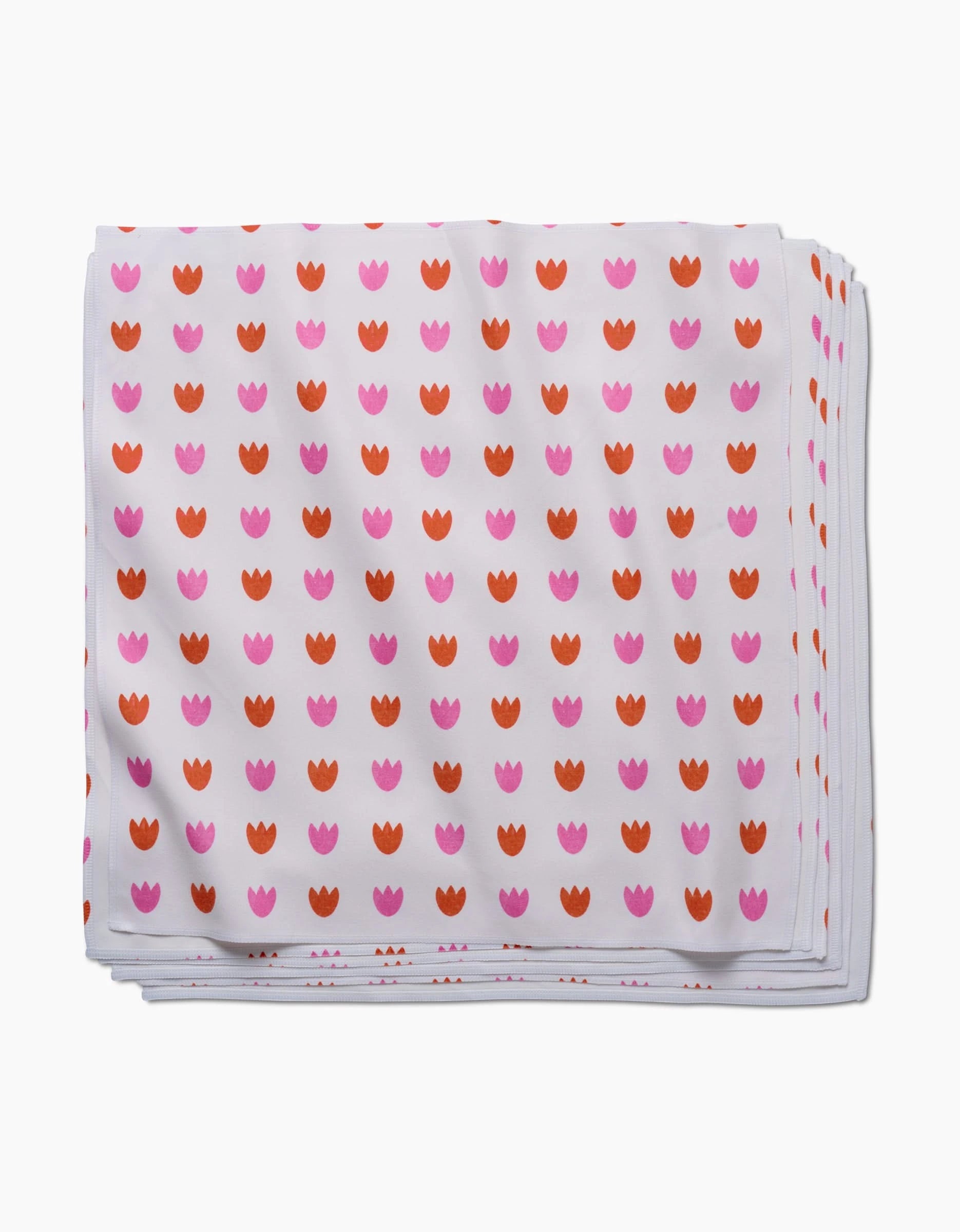 The Addison Dinner Napkin Set by Amy MacCready features folded white Geosuede napkins with a repeating pink and orange tulip-like pattern.
