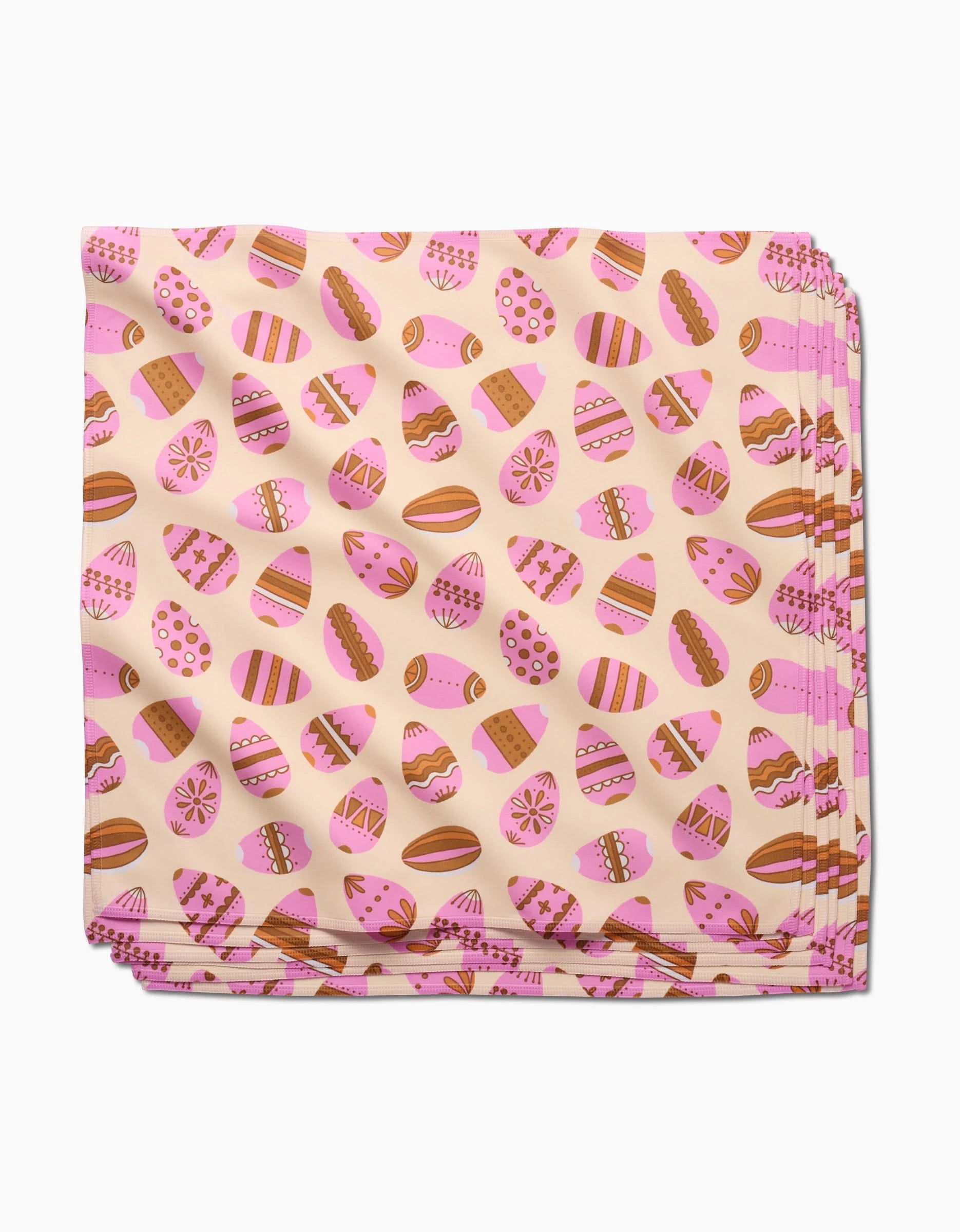 The Arledge napkin by Amy MacCready features eco-friendly recycled fabric with decorated Easter eggs in pink, brown, and white on a pale pink background. Eggs display playful stripes, dots, and zigzags for festive dining.