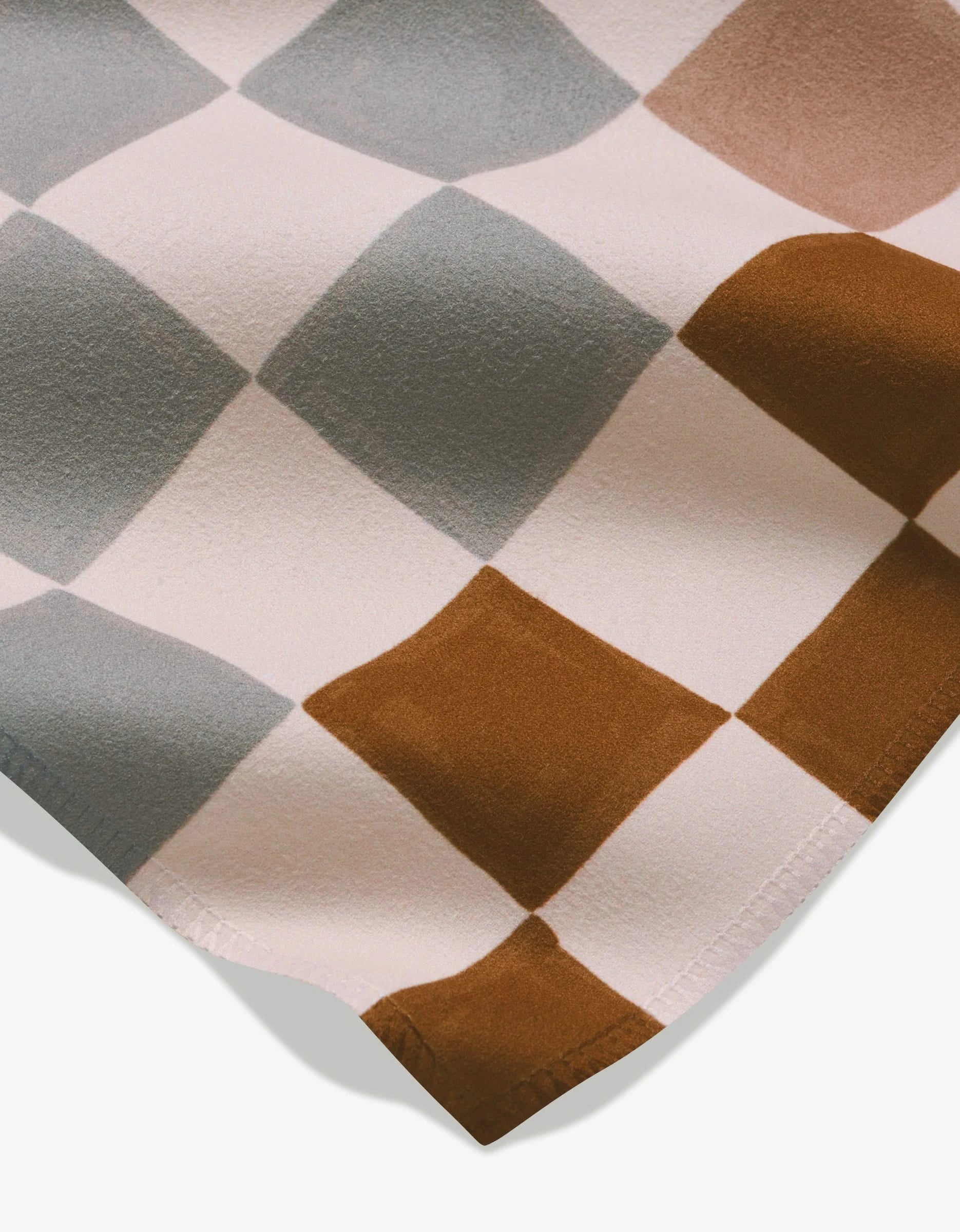 Autumn Checkers by GEOMETRY features soft Geosuede fabric in a checkered pattern with brown, light gray, and off-white squares—smooth and gently folded, ideal for stylish dinner napkins.