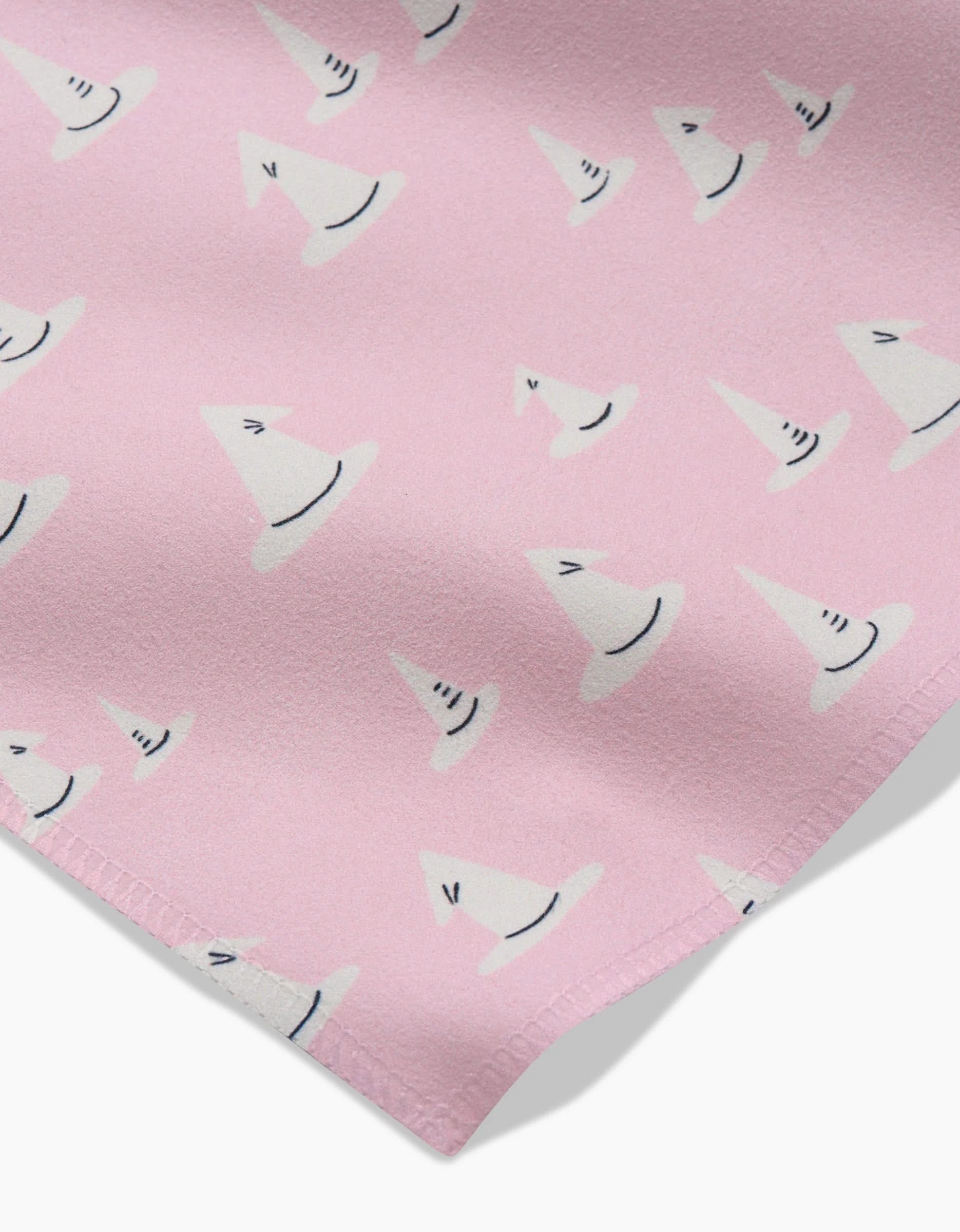 A close-up of Belladonna by Amy MacCready shows pink fabric patterned with small, white witch hats outlined in black—an eco-friendly napkin set perfect for magical gatherings.