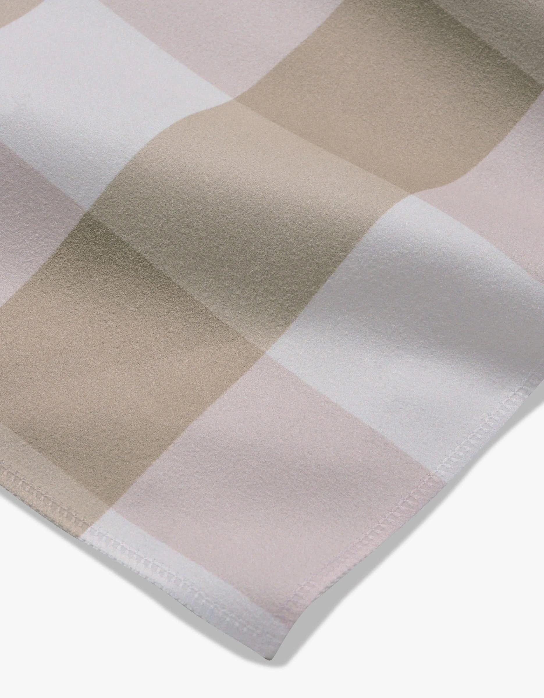 A close-up of the Betty Bakes Dinner Napkin Set by GEOMETRY, featuring Geosuede fabric in a large beige, pink, and white check pattern with a smooth texture and neatly stitched edges—ideal for elegant table settings.
