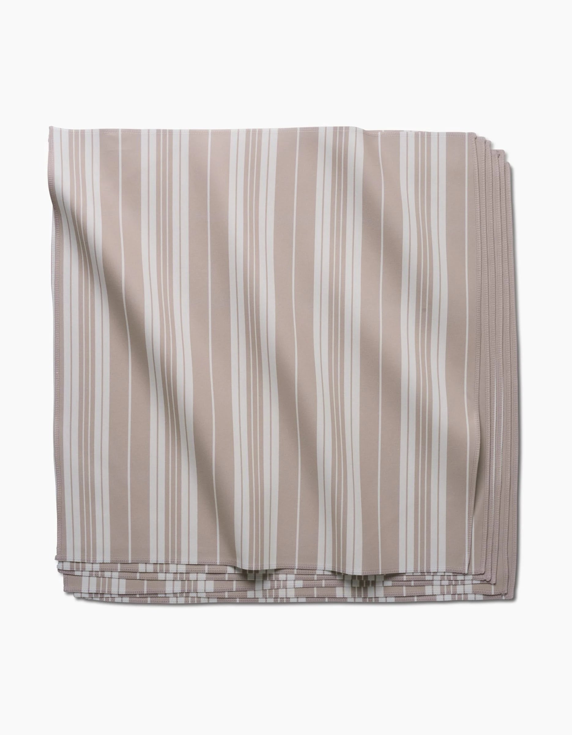 The GEOMETRY Betty Beach dinner napkin set features neatly folded Geosuede fabric with vertical white and beige stripes, displayed against a white background.