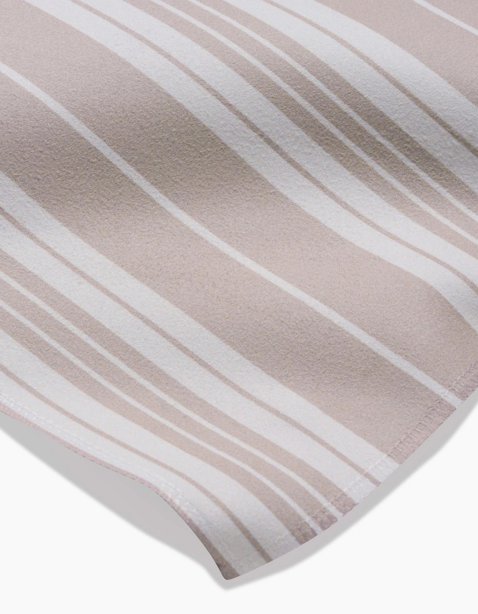 A close-up of the soft Geosuede fabric in beige and white vertical stripes by GEOMETRY, highlighting its smooth texture and curved edge—ideal for the elegant Betty Beach Dinner Napkin Set.