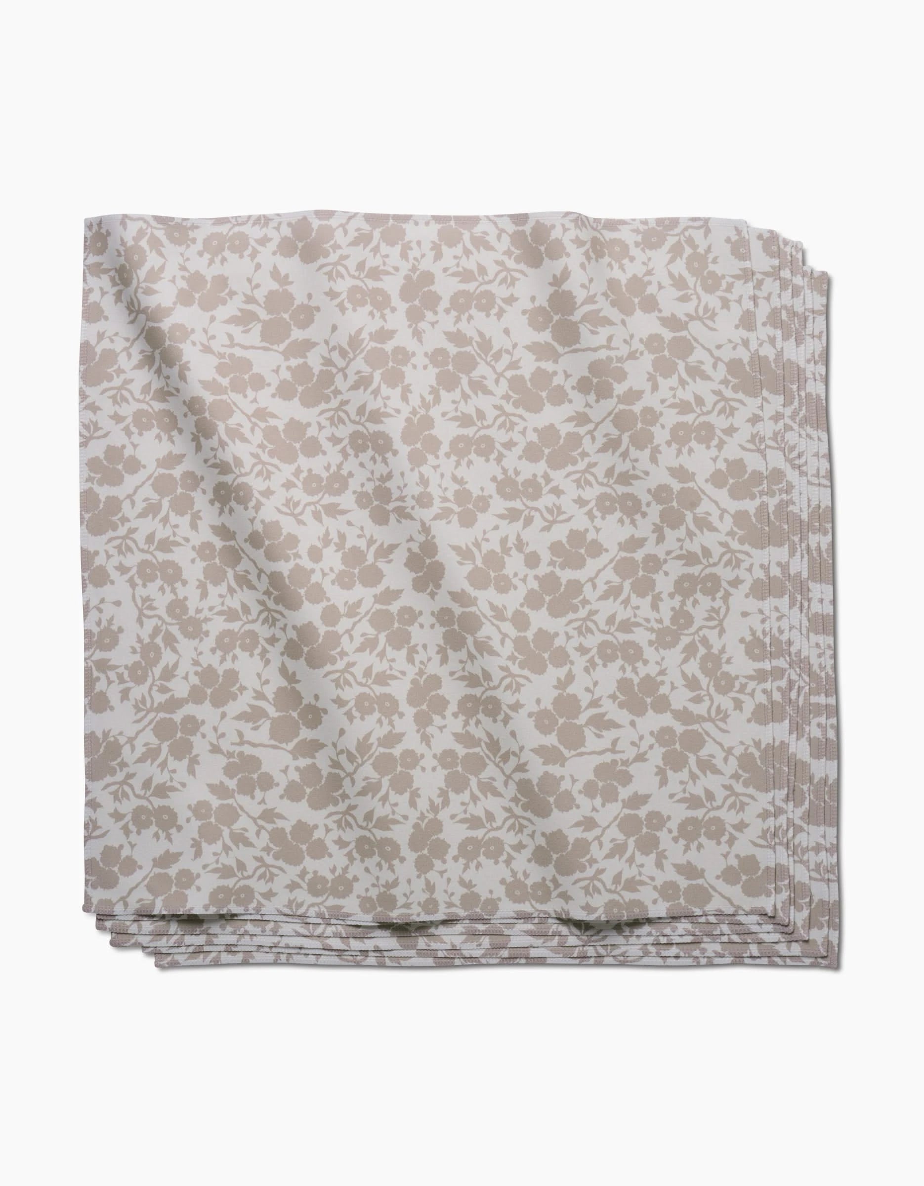 The GEOMETRY Bettys Buds napkin, crafted from Geosuede fabric with a beige and white floral print, is folded and displayed against a white background.