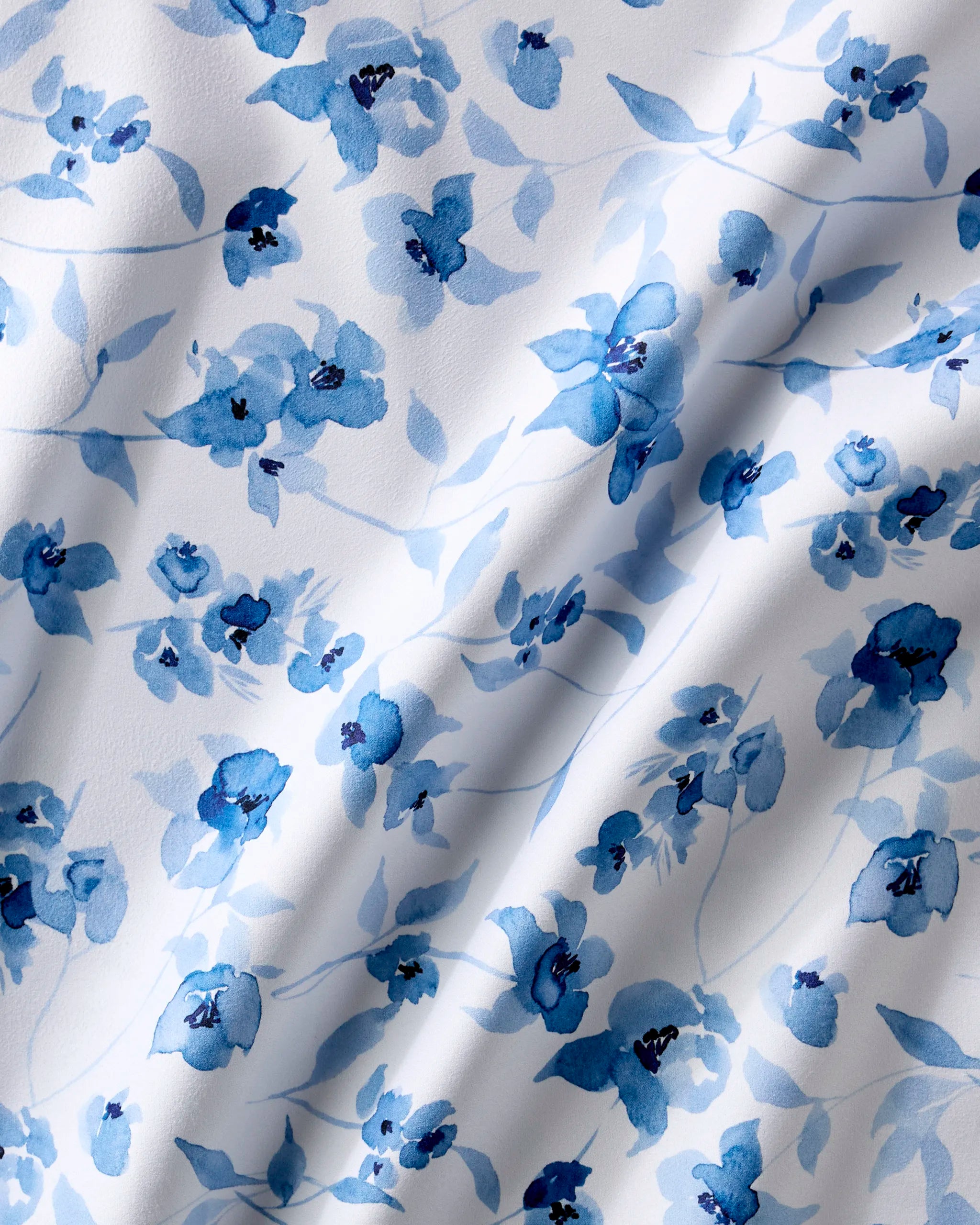 Blue Floral dinner napkins by Aubrey Fairchild feature a white fabric with a watercolor blue floral pattern. Absorbent and soft, these napkins add an elegant touch to any table setting.