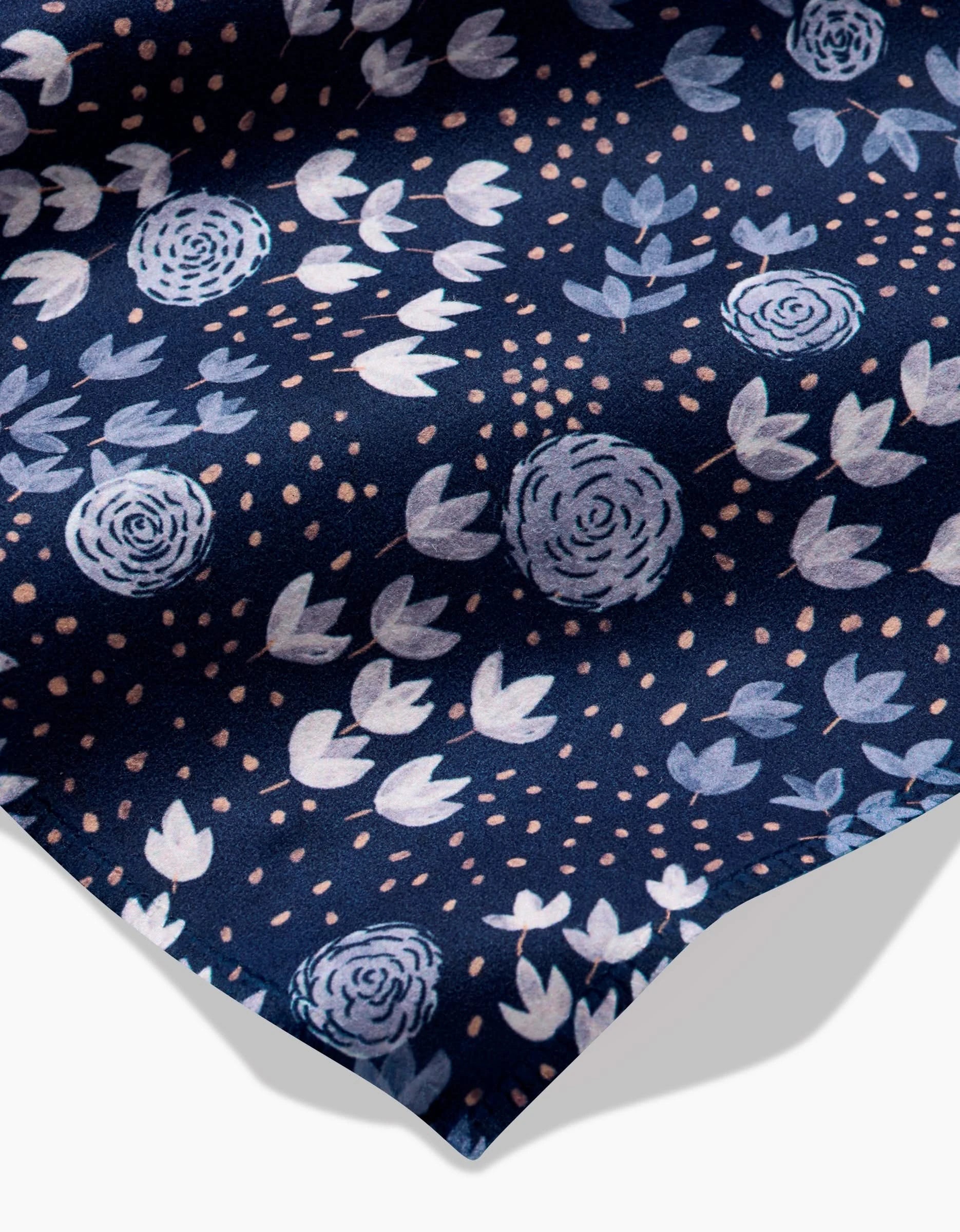 Blue Winter Petal by Katie OShea: a dark blue Geosuede fabric with light blue and white floral patterns and beige dots, slightly draped on a white background—ideal for recycled dinner napkins.