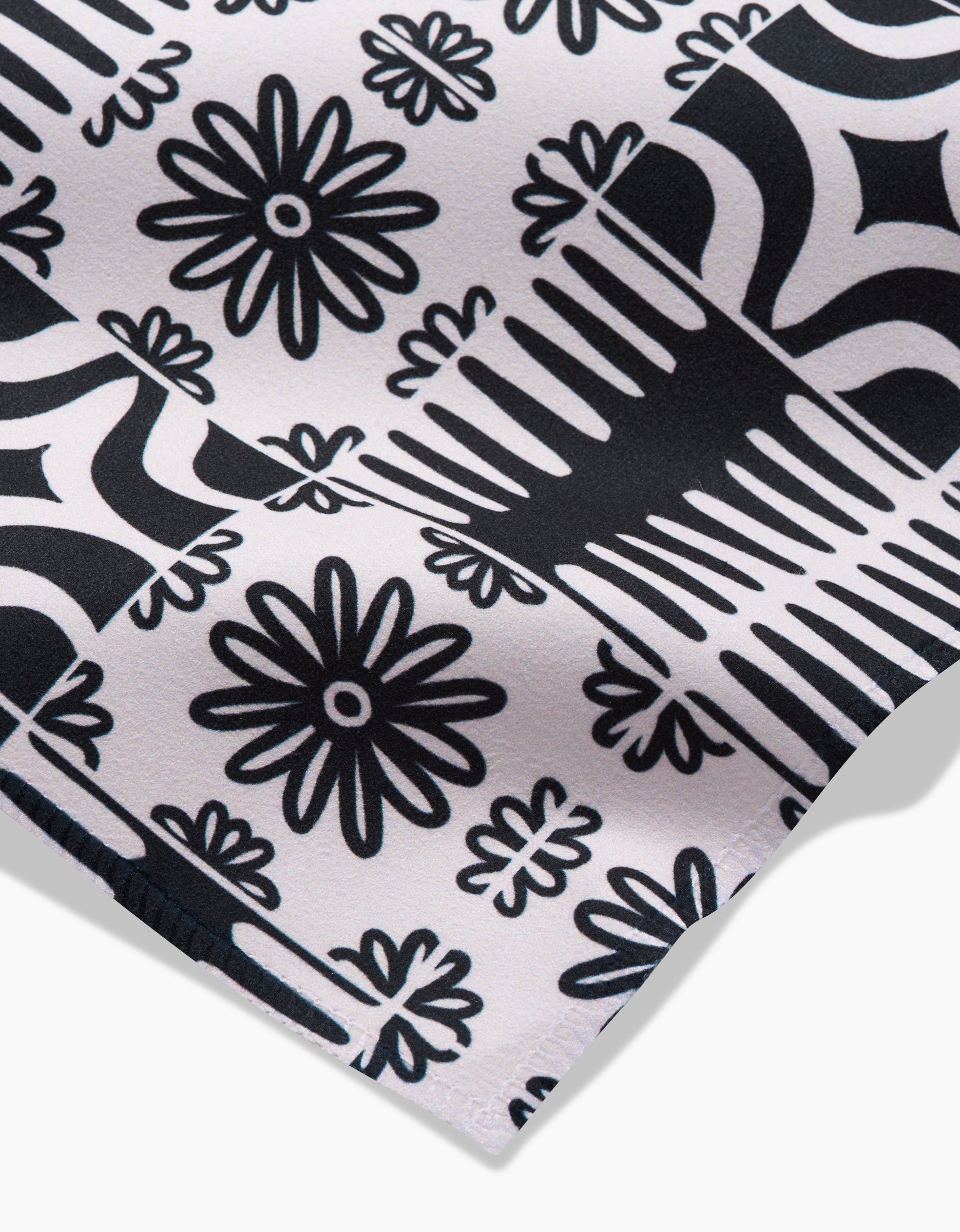 A close-up of Bohemian Mosaic by GEOMETRY, showcasing bold black and white geometric and floral patterns with daisy-like flowers arranged in a grid. Made from recycled materials for an eco-friendly touch.