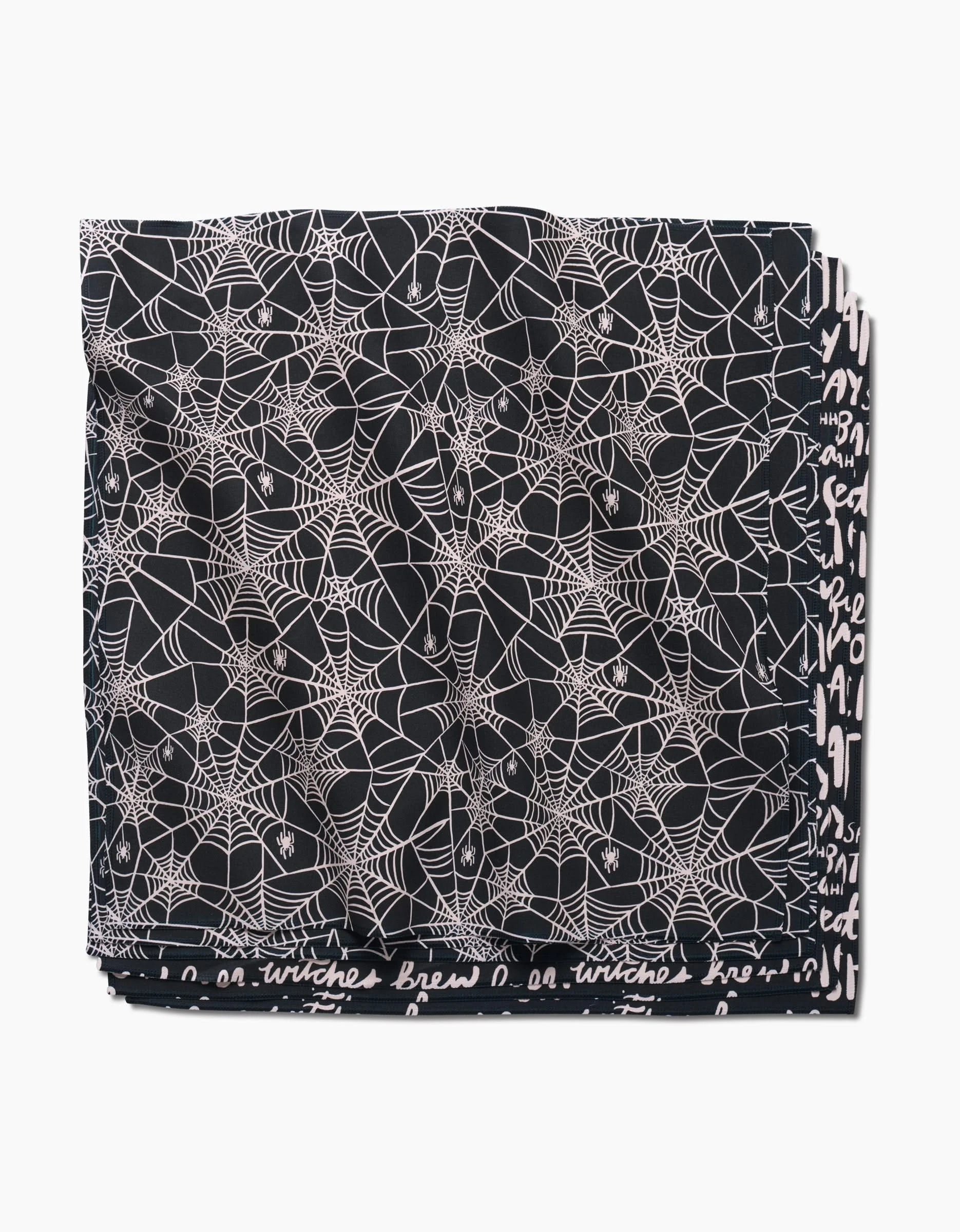 The Kayla Ann Booos Dinner Napkin Set features folded black fabric with a white spiderweb pattern and handwritten-style text. Made from eco-friendly materials, these napkins add a unique, sustainable touch to your table.