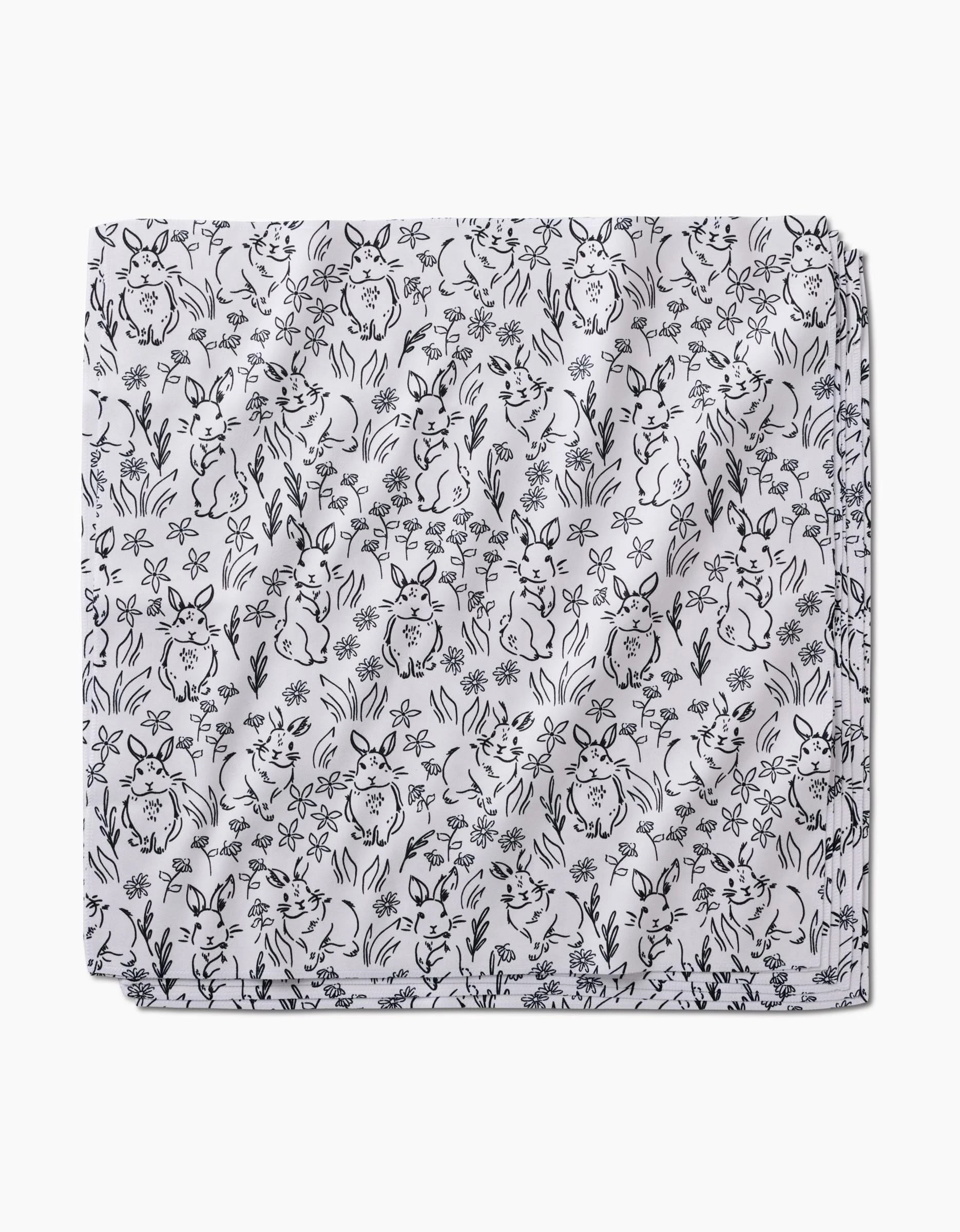 The “Bunny Rabbit Garden” Dinner Napkin Set by Charlie Rowan Designs features white fabric with a black line-art pattern of playful bunnies, flowers, and plants—an eco-friendly way to add whimsical charm to any table setting.