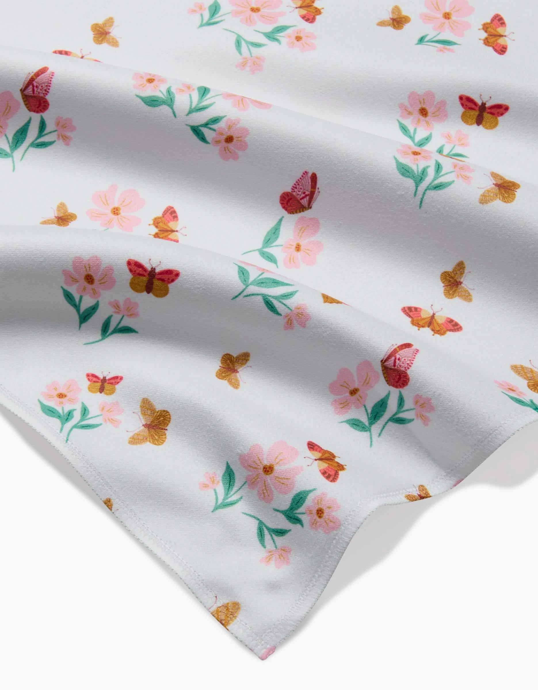The Butterfly Garden blanket by Danelys Sidron is made from white Geosuede fabric and features pink flowers, green leaves, and orange-red butterflies in a scattered pattern.