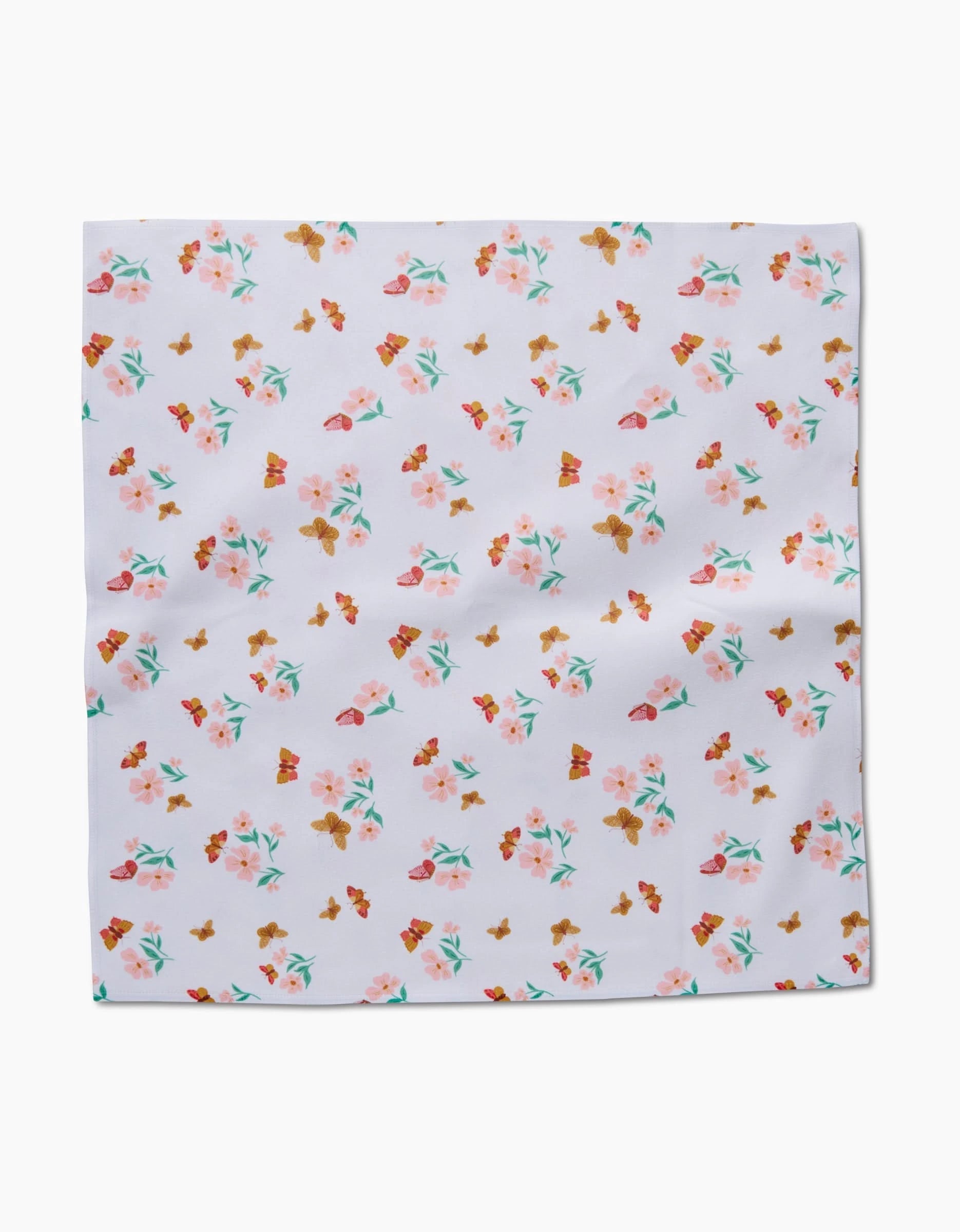 The Butterfly Garden napkin by Danelys Sidron is a square, white Geosuede fabric piece featuring a scattered pattern of small, colorful flowers in pink, orange, and green.