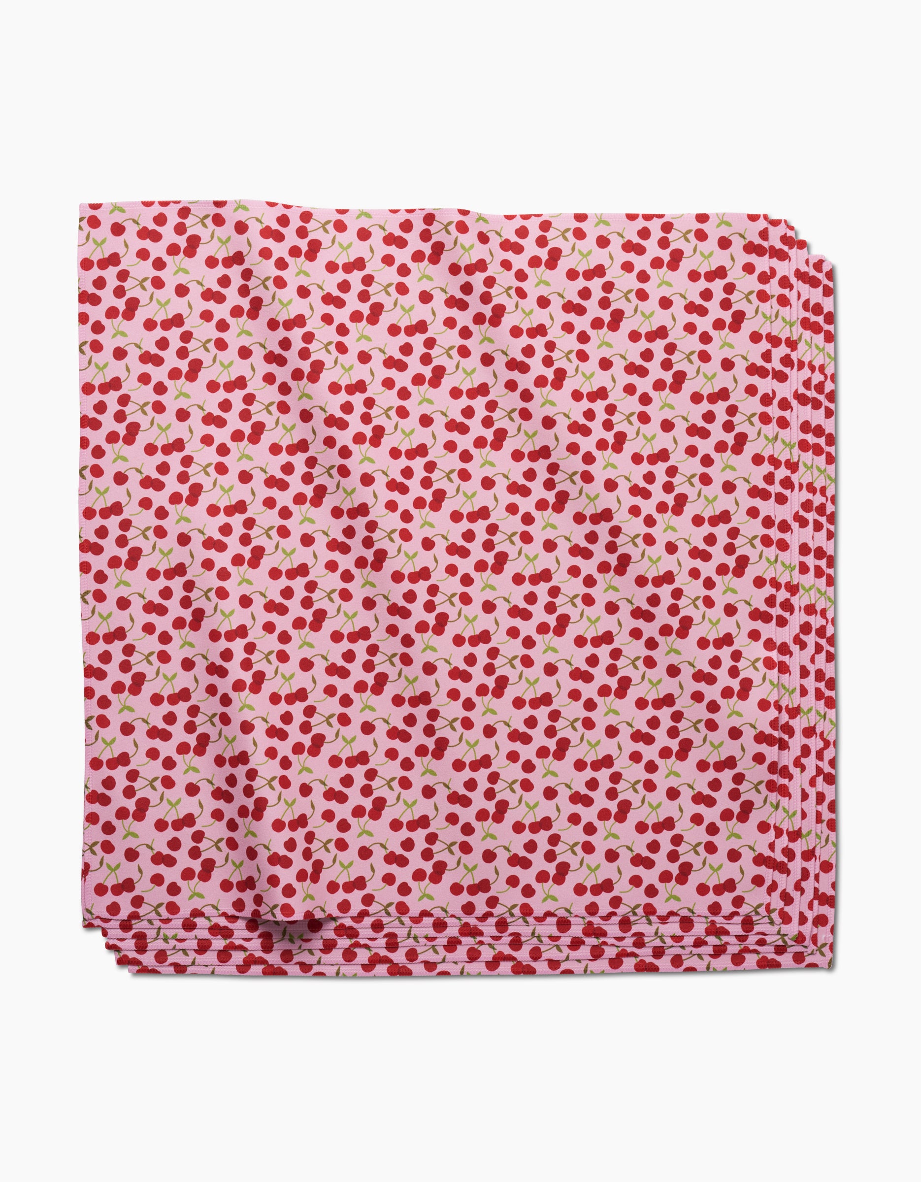 The Cheery Cherries by GEOMETRY features Geosuede fabric with a pink base and red cherries with green stems, made from recycled materials—perfect for creating stylish dinner napkins.