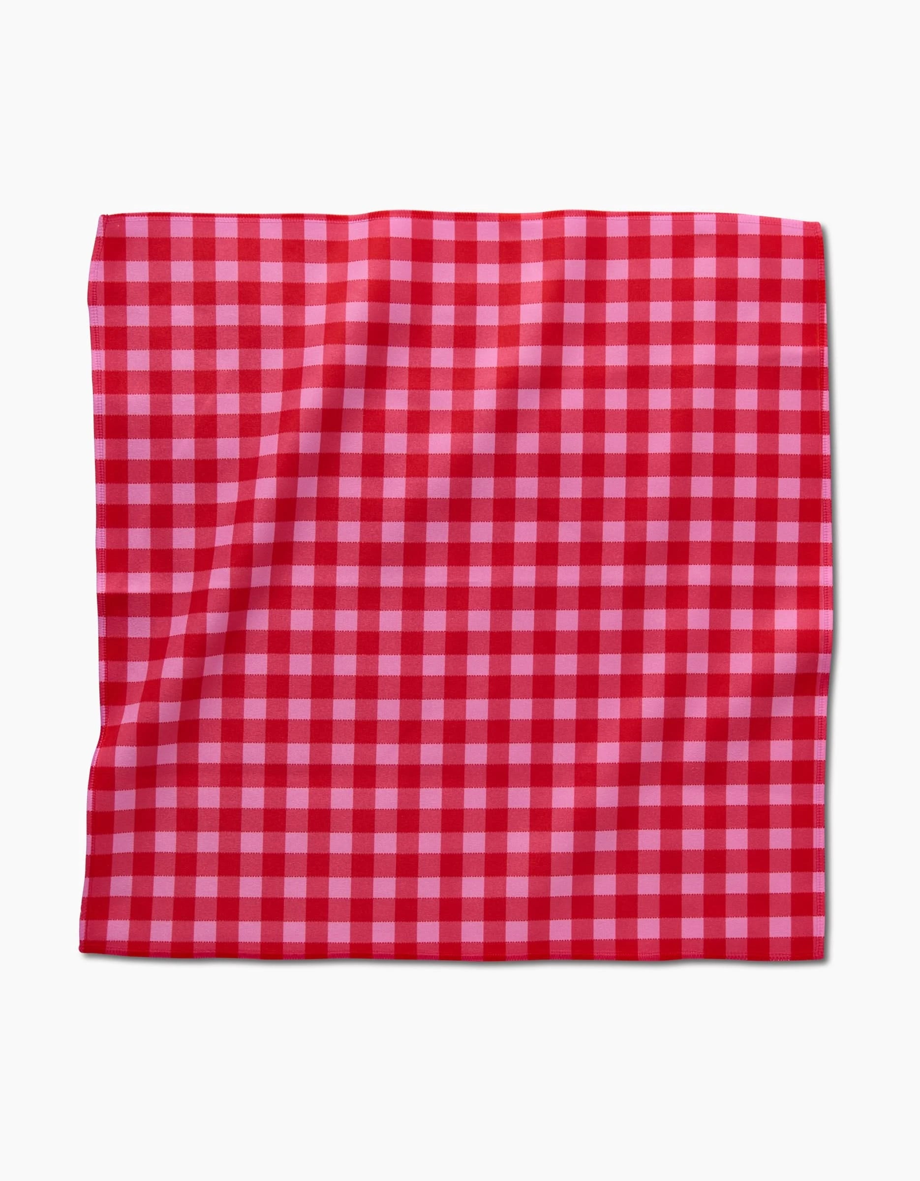 The GEOMETRY Cherry Gingham square dinner napkin, made from Geosuede fabric, features a red and pink gingham checkered pattern and is shown lying flat on a white background.