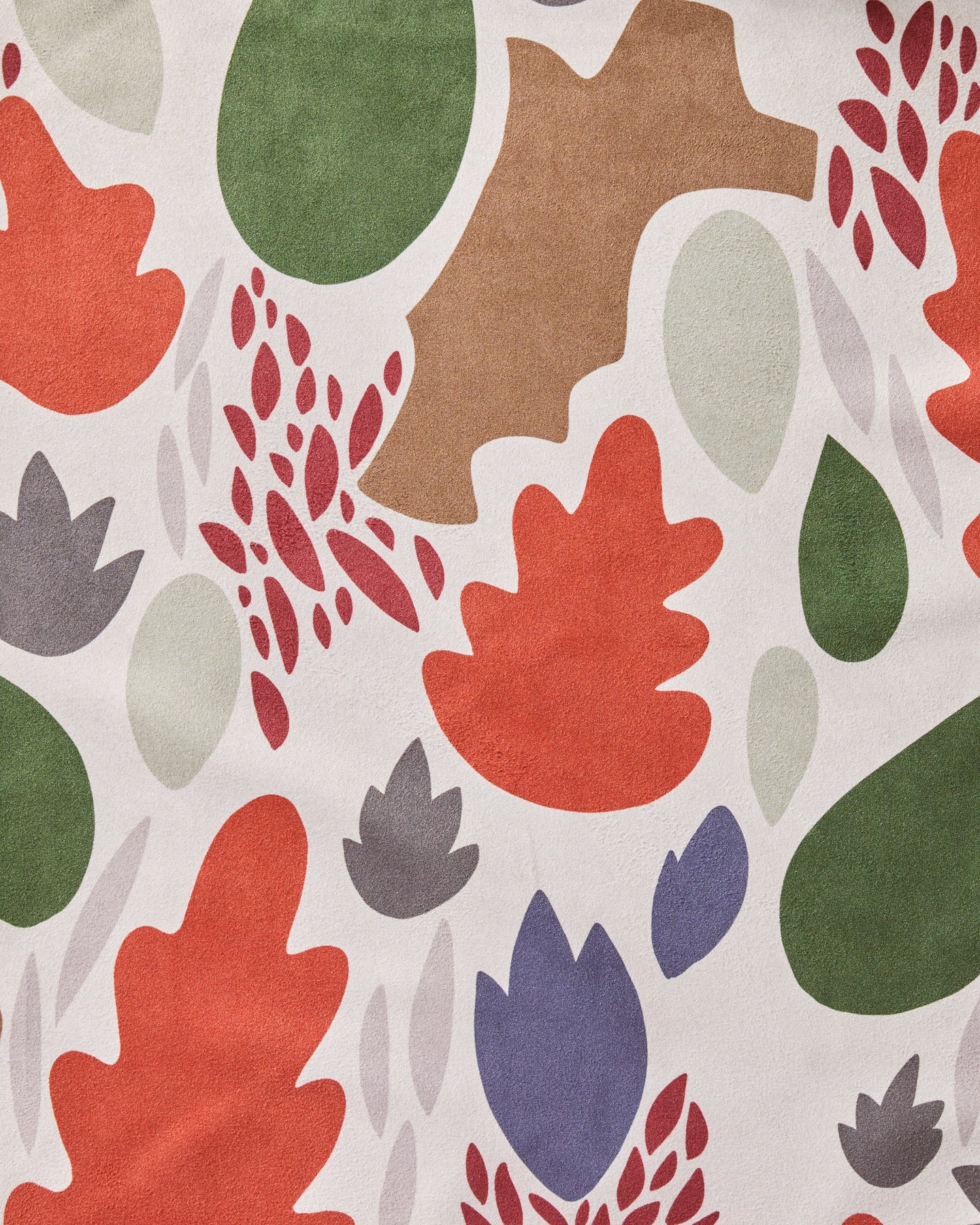 The Geometry Cut Paper Leaves Cream dinner napkin set features a bold, nature-inspired abstract pattern with red, orange, green, purple, brown, and beige leaves on cream and is crafted from recycled materials.
