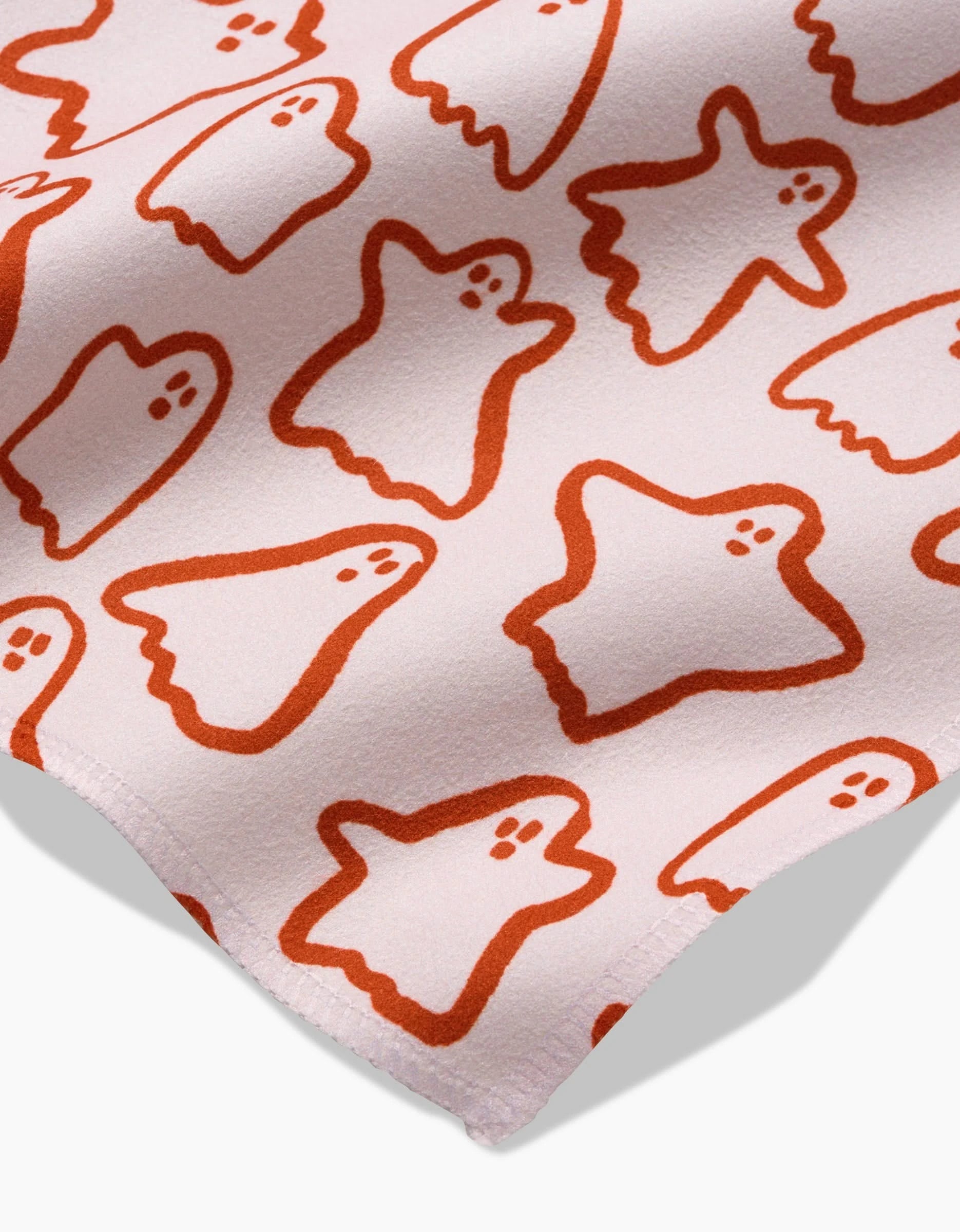 A close-up of Kayla Anns Cute Ghosts shows soft pink Geosuede fabric with simple orange cartoon ghosts, each outlined and featuring small dot eyes and mouths.