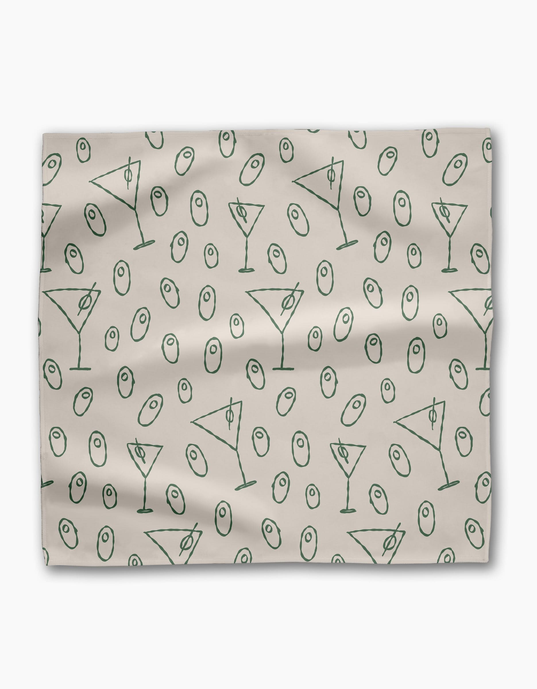The Dirty Martini dinner napkin set by Rosa Kichline is light beige, made from recycled fabric, and showcases a repeating pattern of green martini glasses and green olives scattered across the surface.