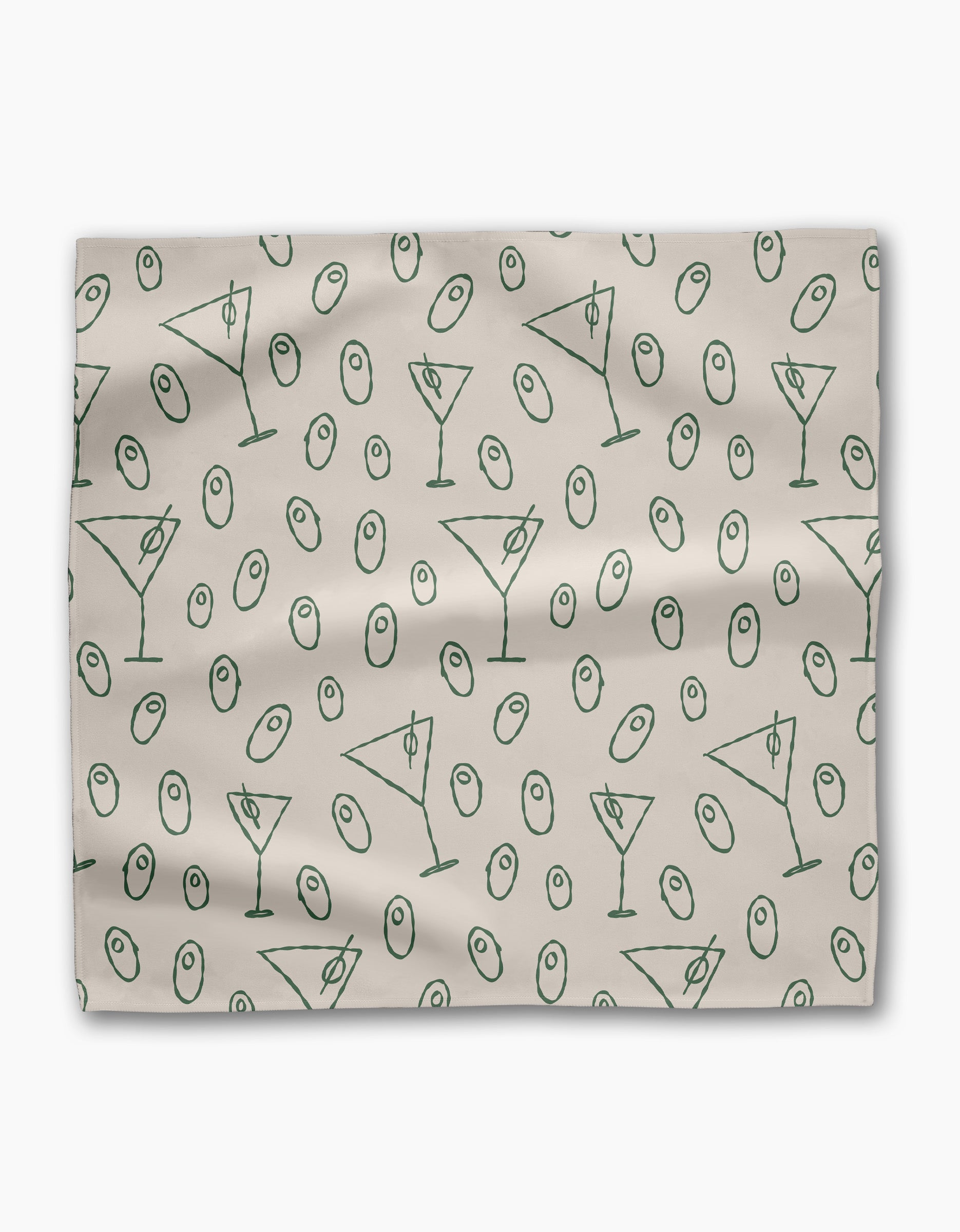 The Dirty Martini dinner napkin set by Rosa Kichline is light beige, made from recycled fabric, and showcases a repeating pattern of green martini glasses and green olives scattered across the surface.