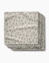 A stack of Rosa Kichline Dirty Martini beige recycled dinner napkins, featuring a repeating pattern of green martini glasses and olives.