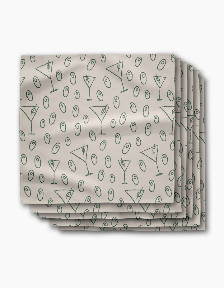 A stack of Rosa Kichline Dirty Martini beige recycled dinner napkins, featuring a repeating pattern of green martini glasses and olives.