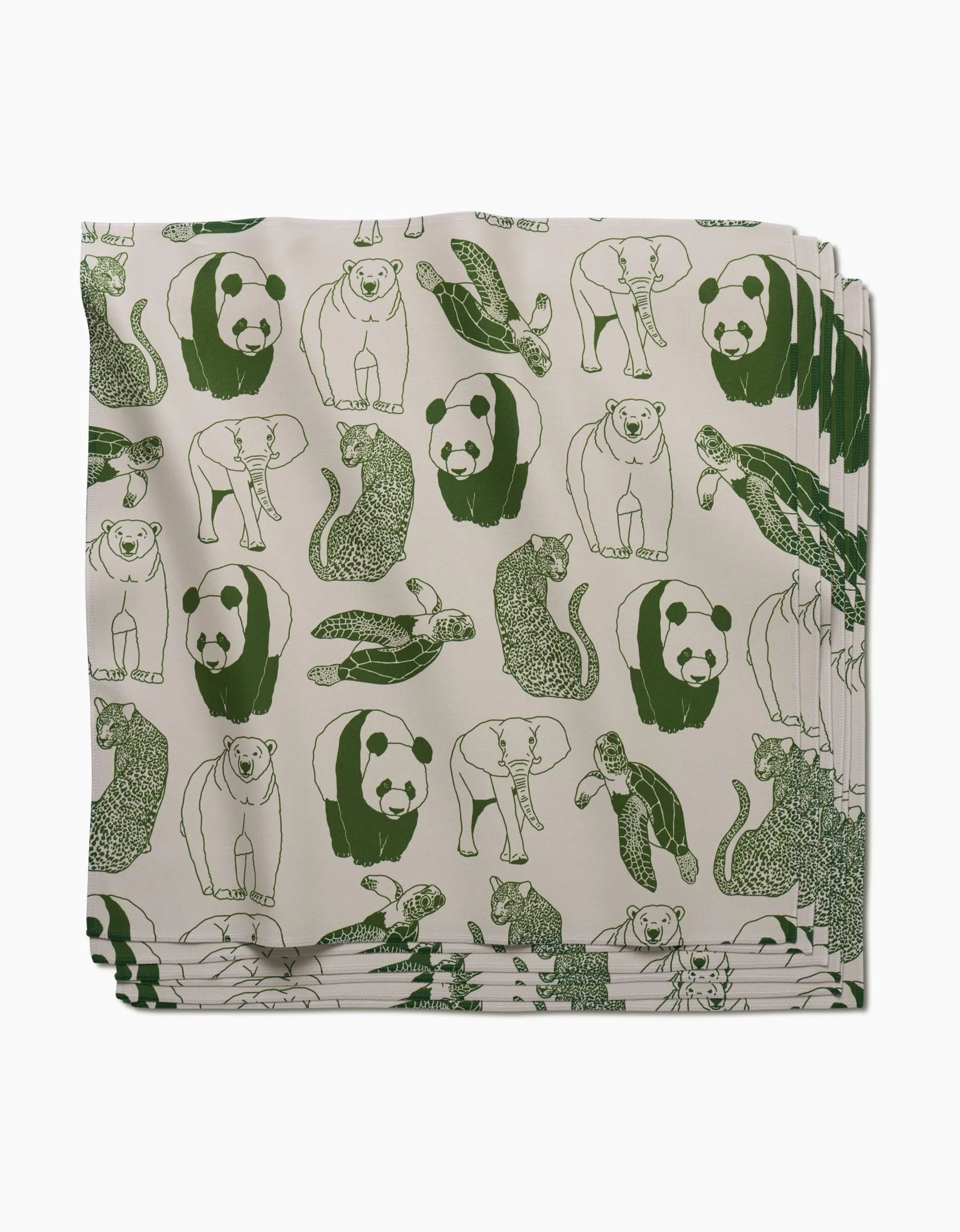 The GEOMETRY Endangered dinner napkin set, made from soft Geosuede fabric, features green line drawings of pandas, sea turtles, seals, and lizards on a cream background.