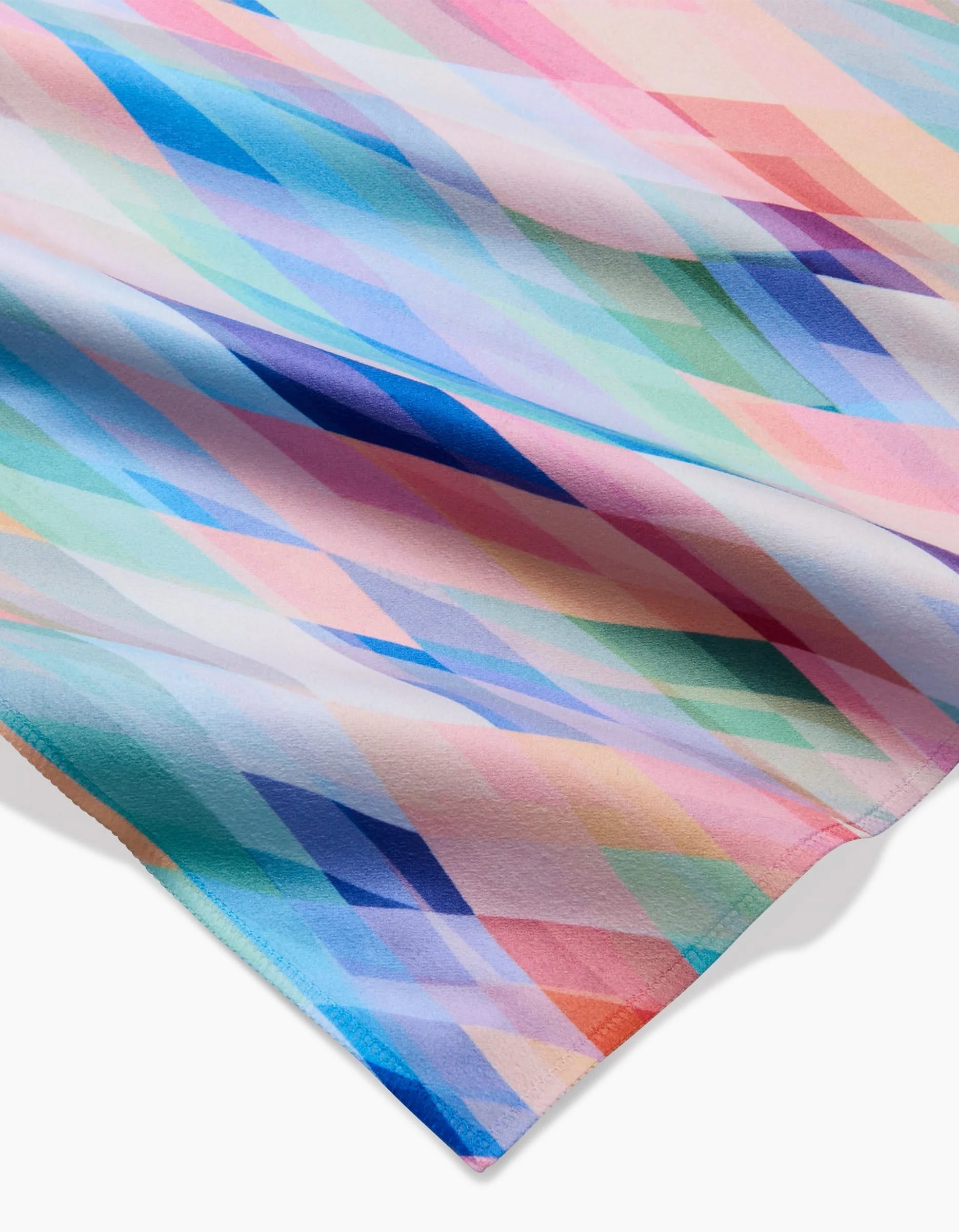 Eventide eco-friendly napkins by Rachel Parker feature a close-up of Geosuede fabric with an abstract geometric diamond pattern in pastel pink, blue, green, purple, and peach for a soft and colorful look.