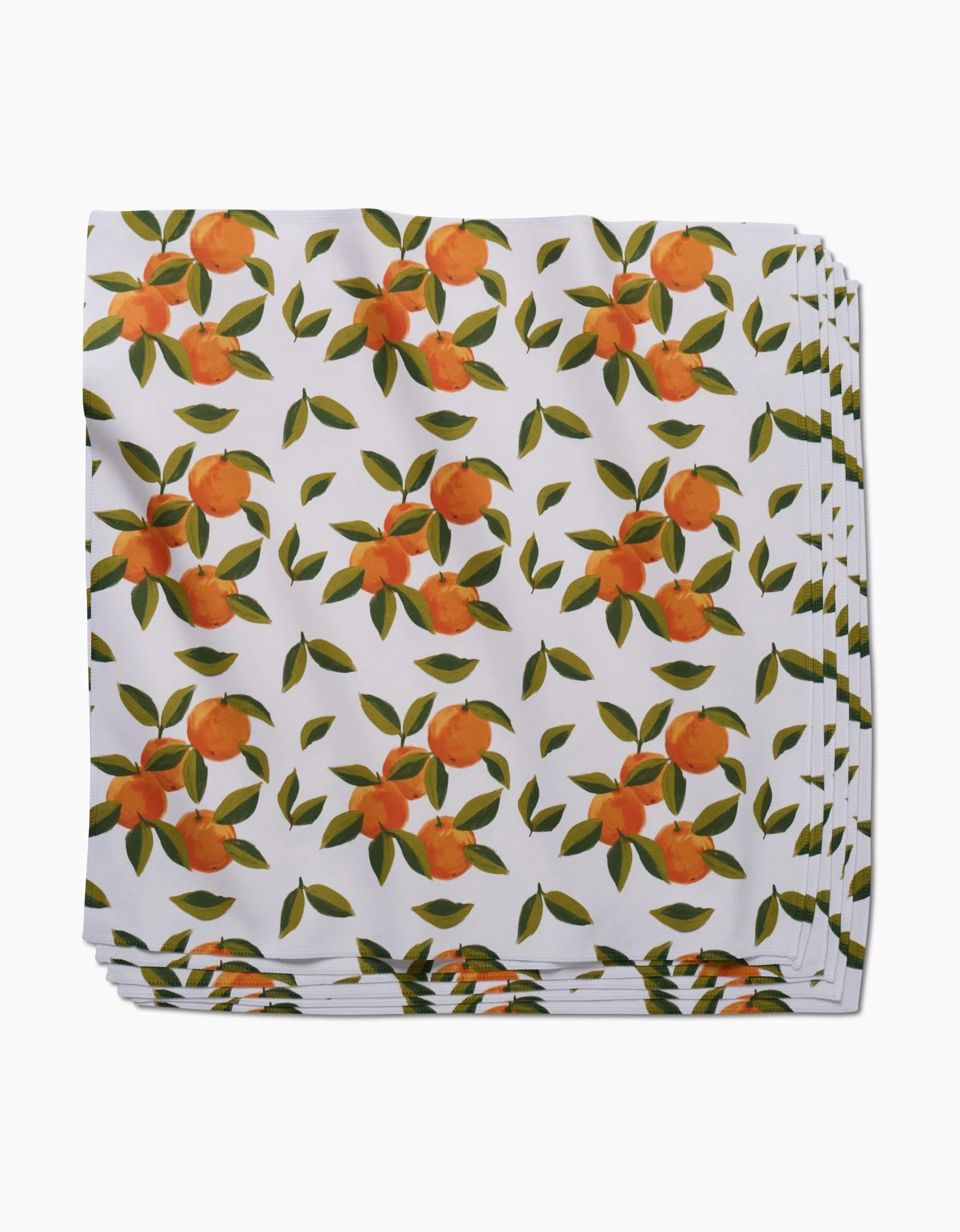 The GEOMETRY Fallbrook Oranges dinner napkin set features neatly folded white napkins with a vibrant orange fruit and green leaf pattern, crafted from soft Geosuede fabric.