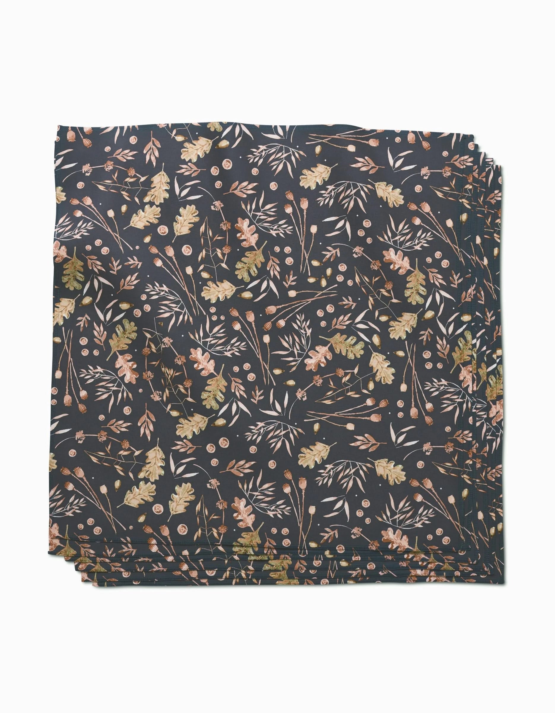 A stack of Fallen Oak Geosuede fabric by Katie OShea, featuring a delicate leaf, branch, and flower pattern in earthy pink, gold, and green tones on a dark background—crafted from post-consumer recycled materials.