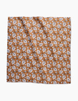 The Falling Acorns Dinner Napkin Set by Charlie Rowan Designs features a square, eco-friendly cloth with a white and black oak leaf pattern on brown, accented by scattered white dots and a slightly wrinkled texture.
