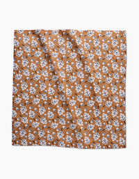 The Falling Acorns Dinner Napkin Set by Charlie Rowan Designs features a square, eco-friendly cloth with a white and black oak leaf pattern on brown, accented by scattered white dots and a slightly wrinkled texture.