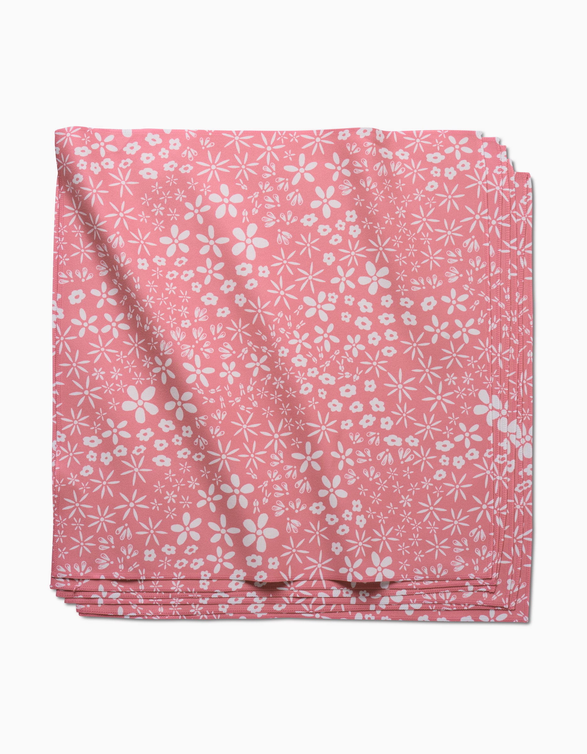 Field of Flowers by Hufton Studio: a folded pink geosuede dinner napkin with a white floral pattern of assorted small flowers, shown on a white background.